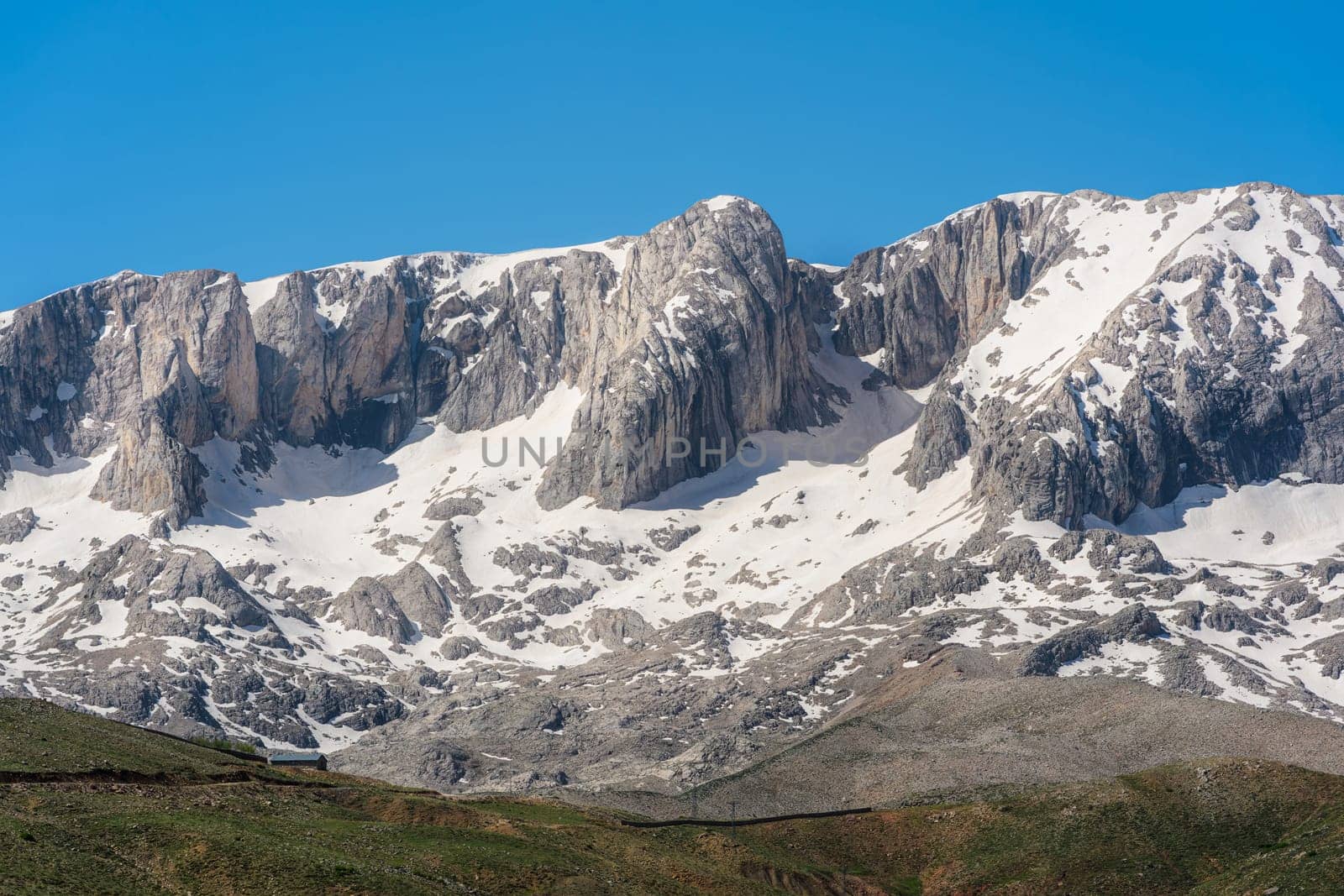 The lush green Sobucimen plateau in spring and the mountains with some melted snow behind.