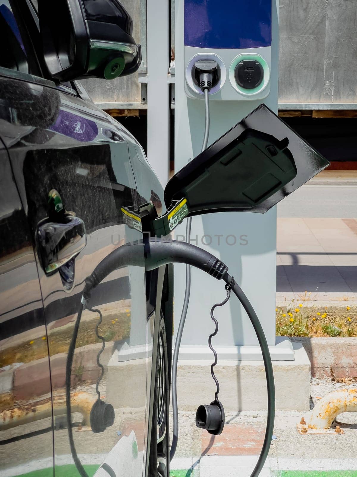 An electric car charging at the Electric vehicle charging station in the parking lot by Sonat