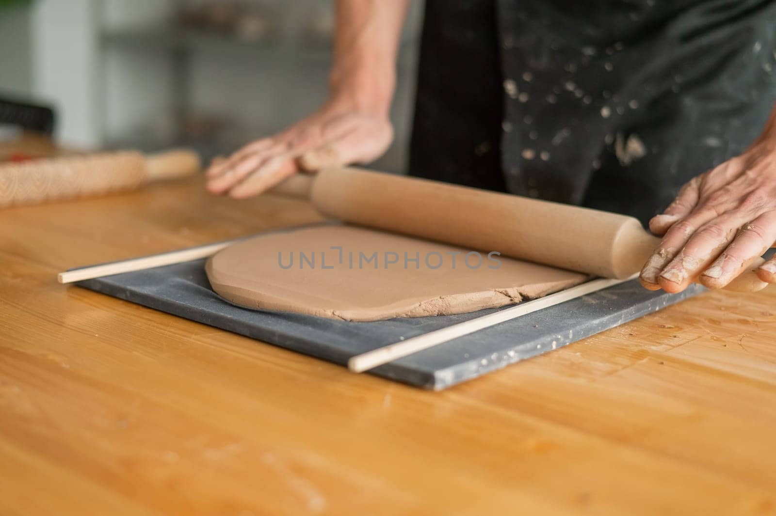 Close-up of potter's hands rolling out clay