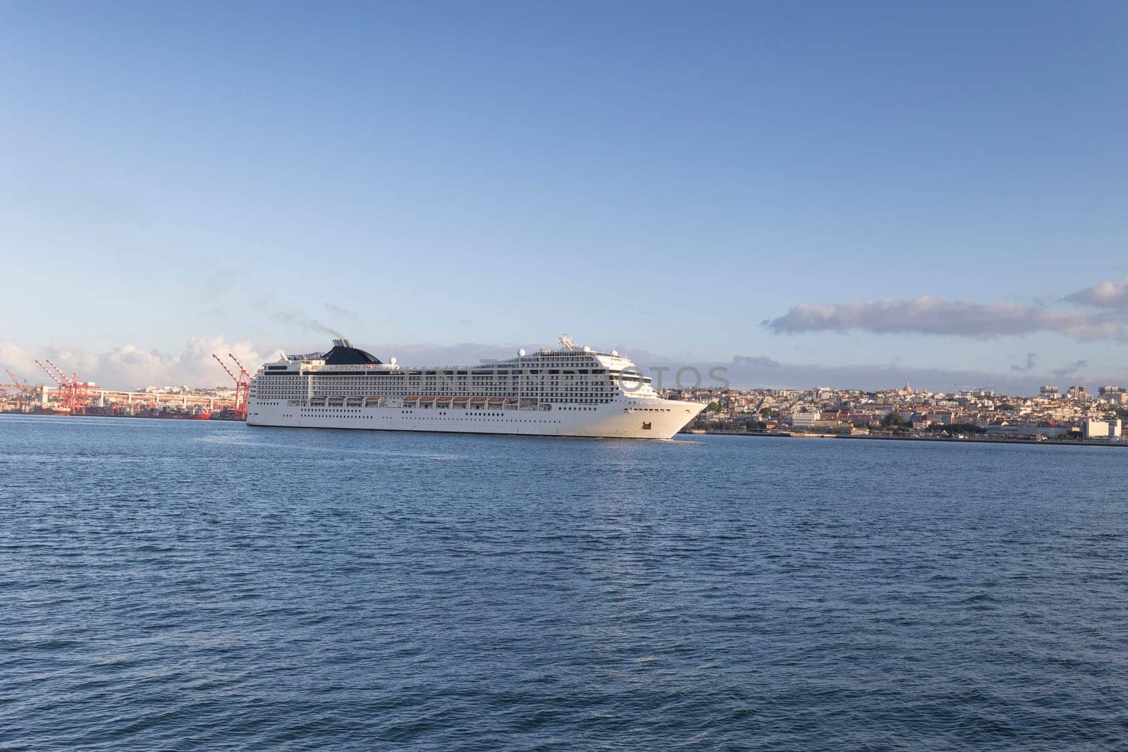 A large cruise ship is sailing in the ocean. The sky is clear and the water is calm