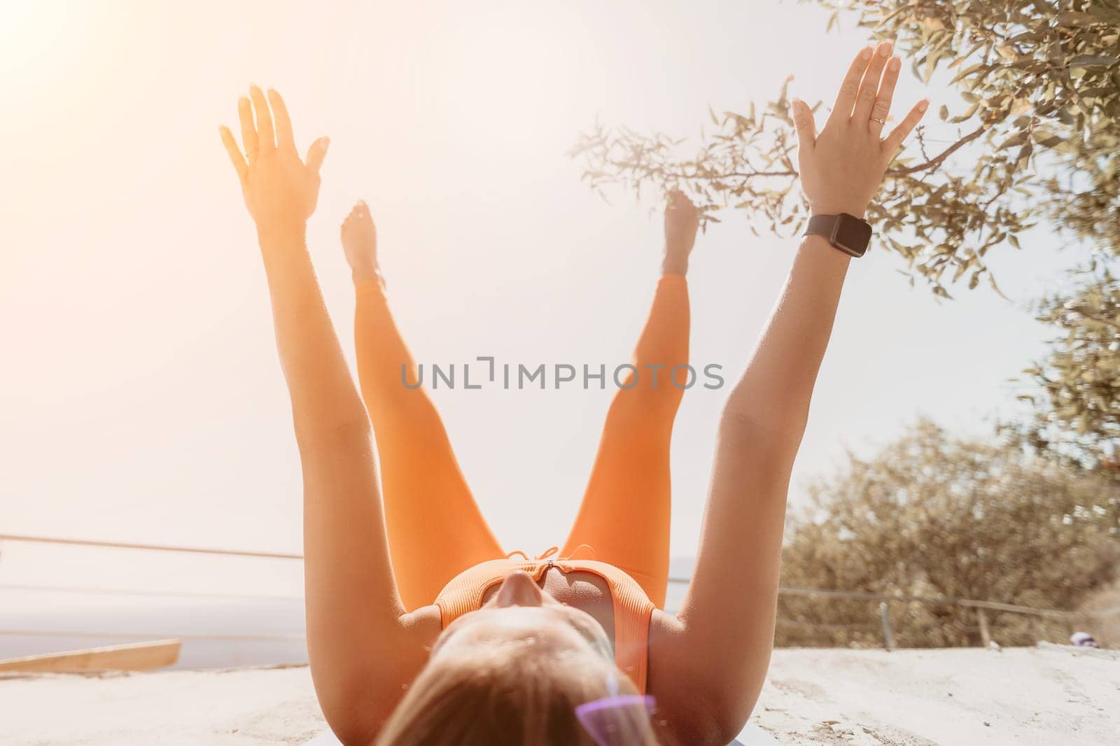 Fitness woman sea. Outdoor workout on yoga mat in park near to ocean beach. Female fitness pilates yoga routine concept. Healthy lifestyle. Happy fit woman exercising with rubber band in park.