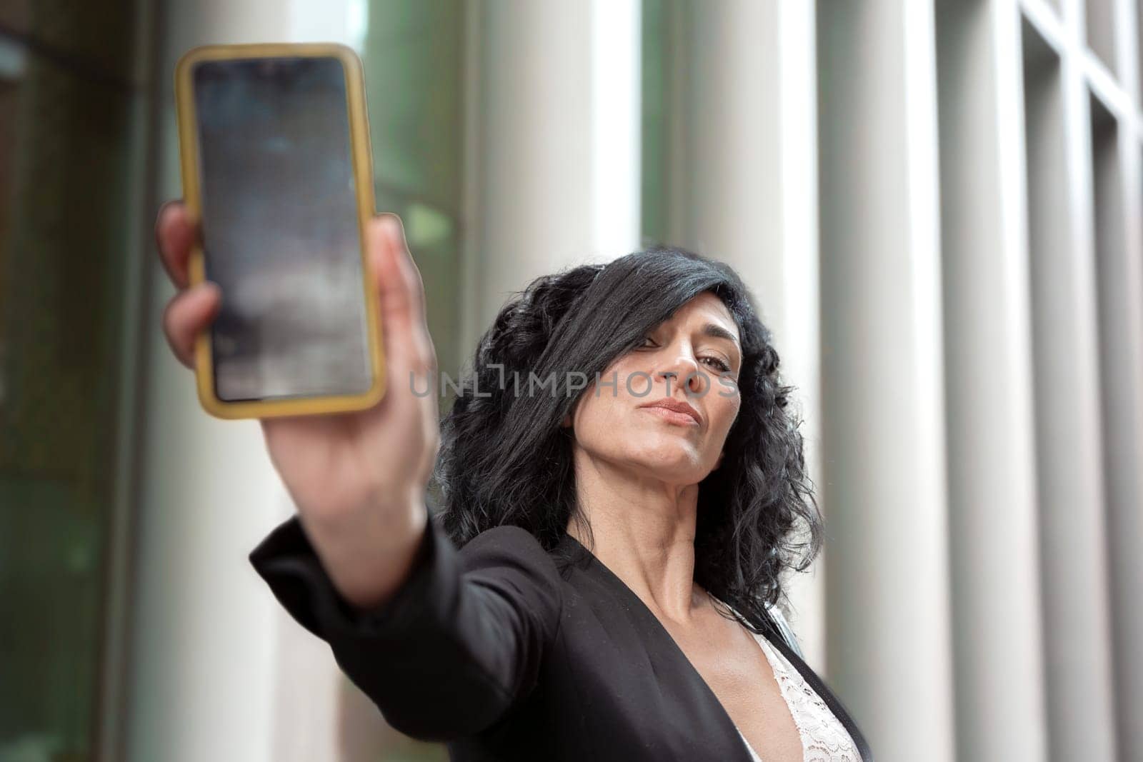 Happy woman smiling pointing to empty smartphone screen outdoors by mariaphoto3