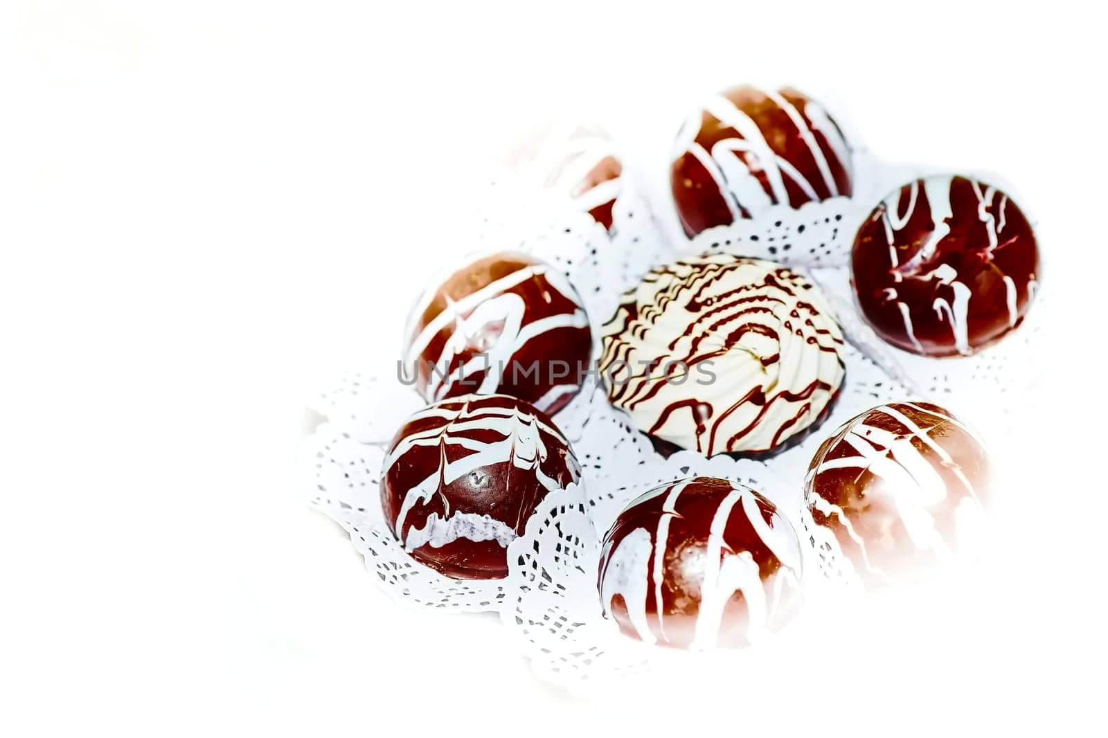 Set of round chocolate candies, decorated with lines of white cream by jovani68