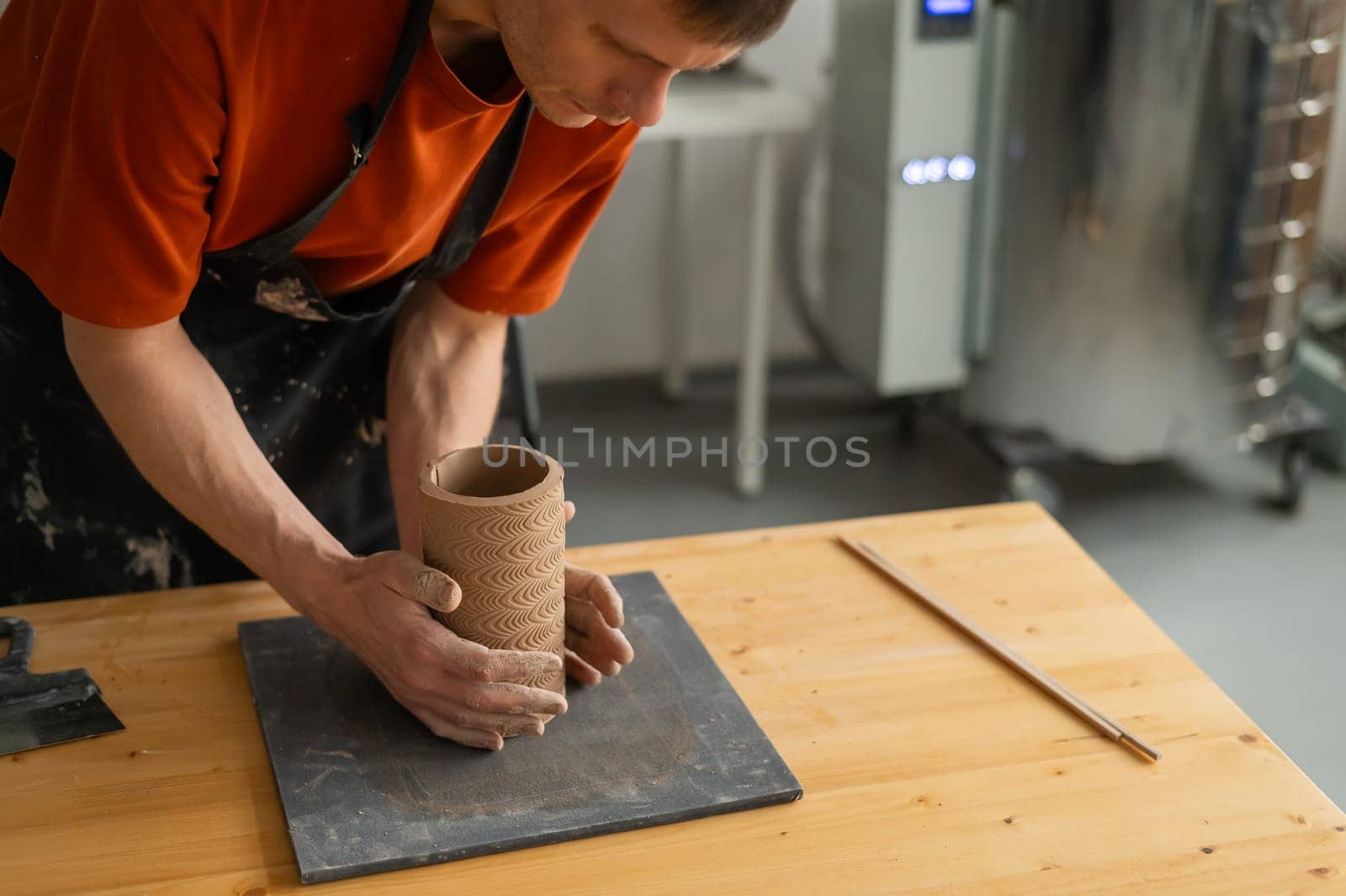 Close-up of a man's hands making a patterned cylinder out of clay. by mrwed54