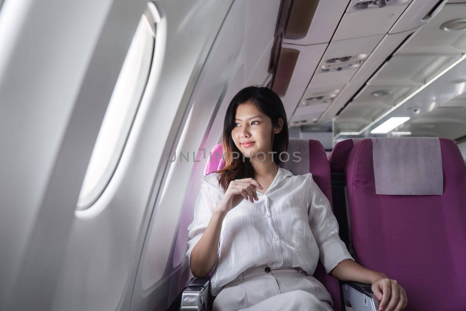 Businesswoman smiling while sitting in airplane seat. Concept of business travel and professional journey.