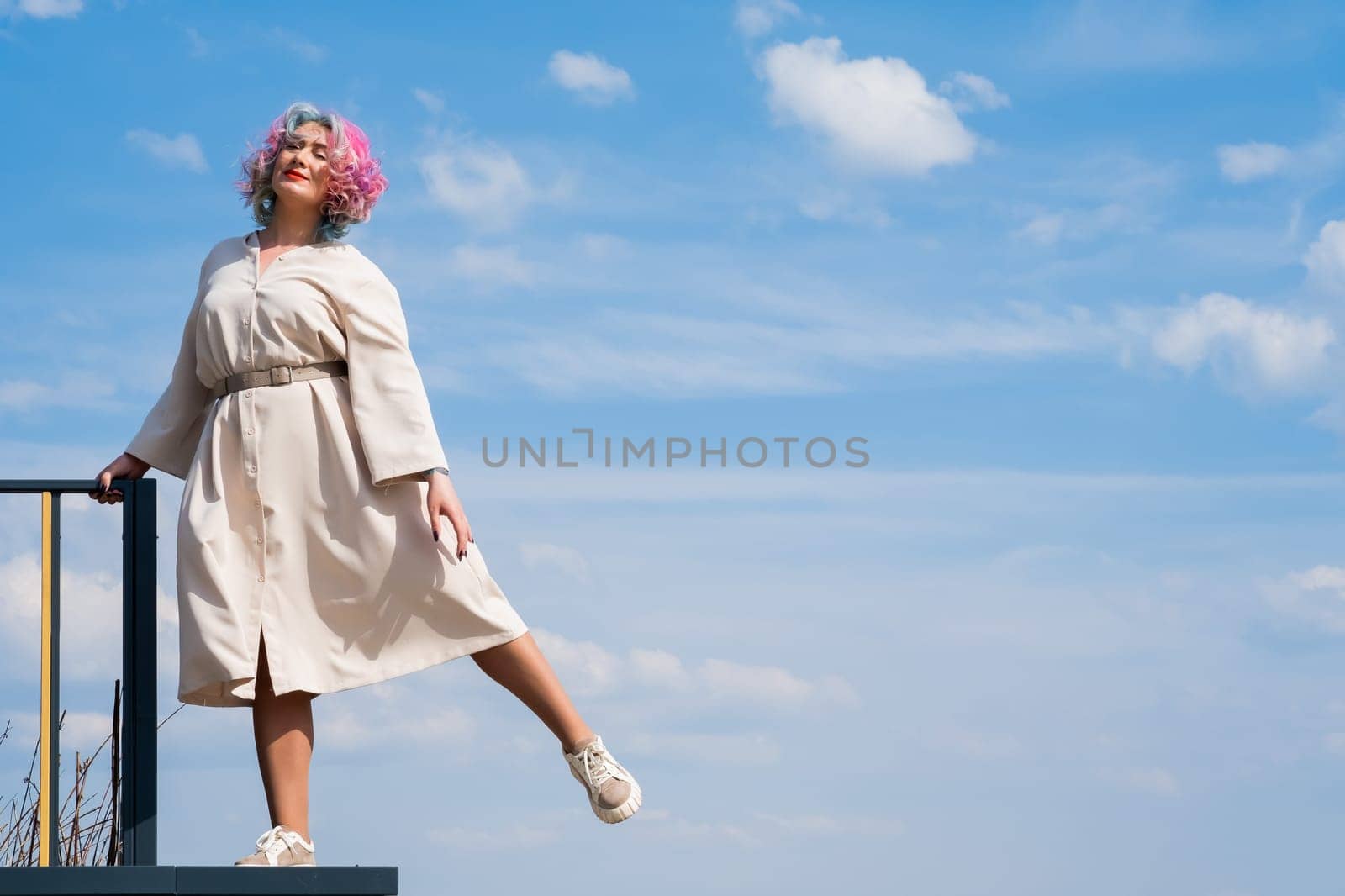 A woman with colored hair walks outdoors. Portrait of a girl against the blue sky. by mrwed54