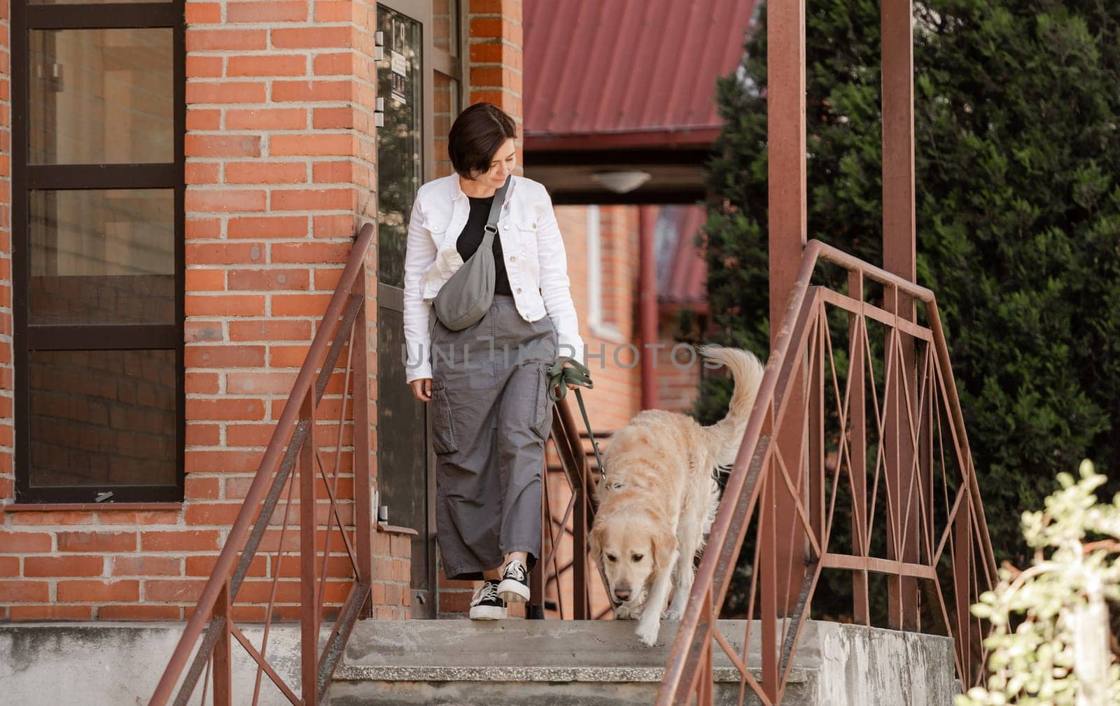 Young Woman Steps Out Of House For A Summer Walk With Golden Retriever