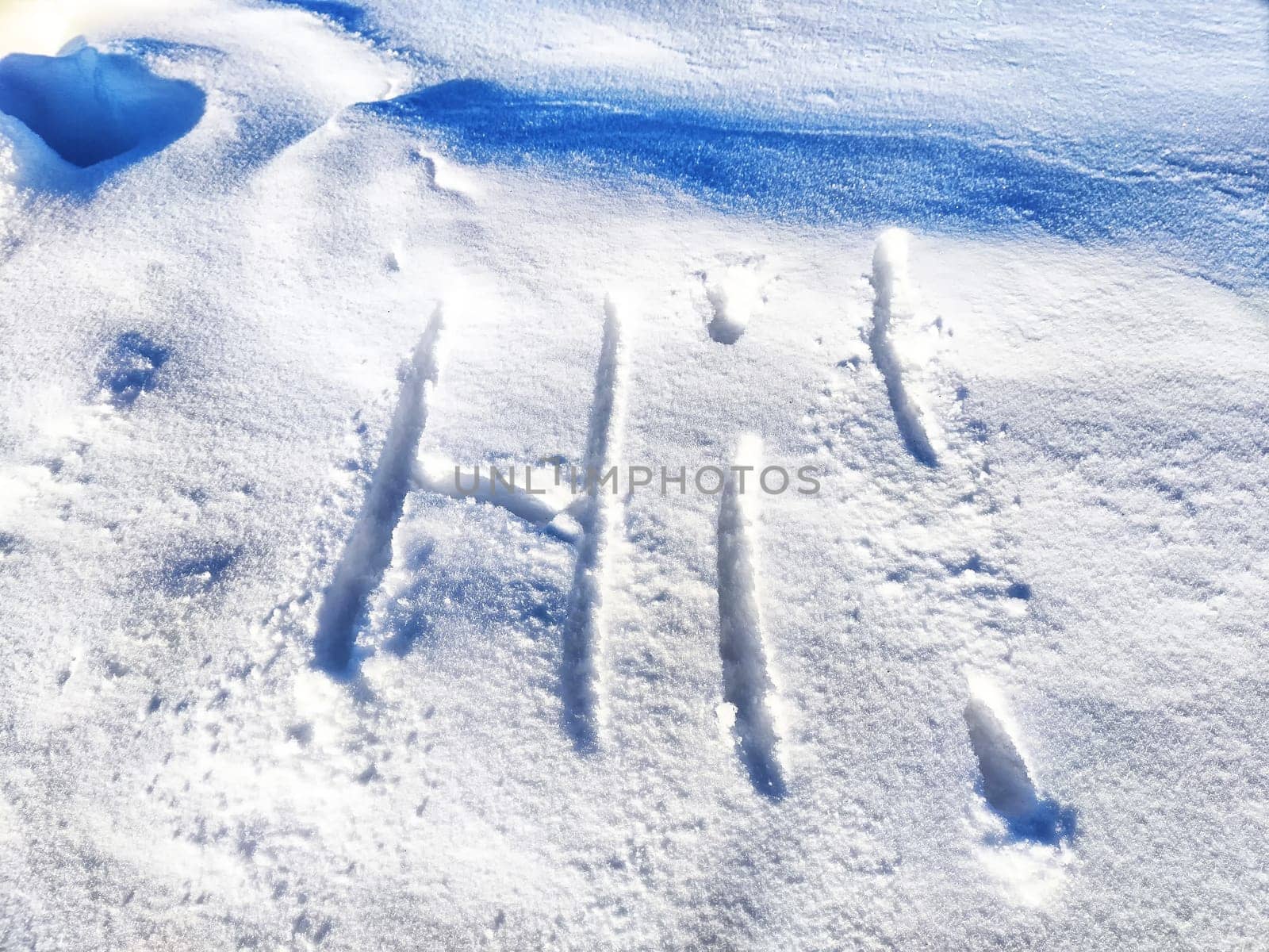 Inscription Hi, written on white background of the snow. Top view. Flat lay. New year and Christmas. Greeting morning, day, weather, sun and people