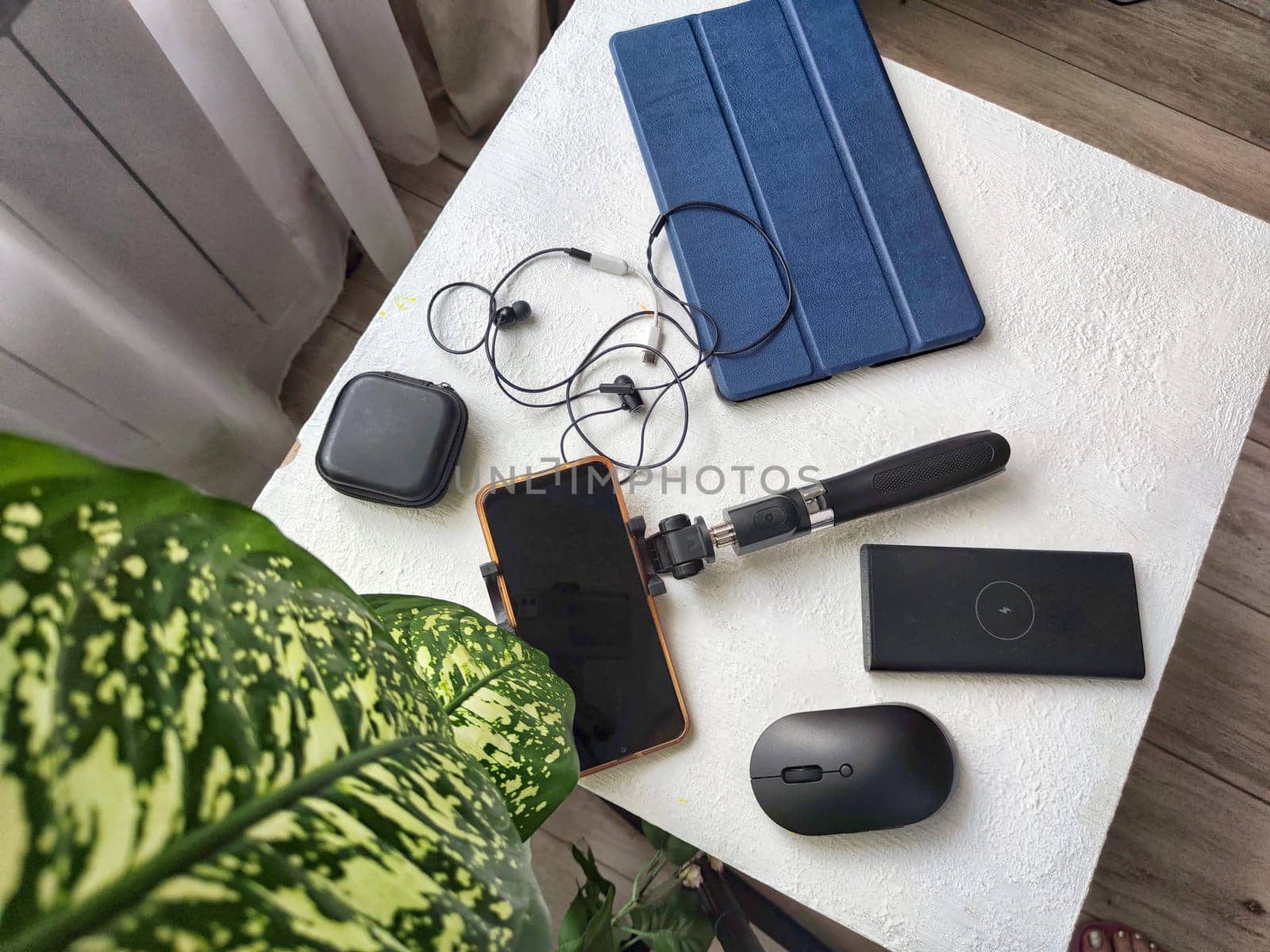 A set of useful blogger devices. A neatly organized desk featuring a smartphone, earphones, and various tech gadgets