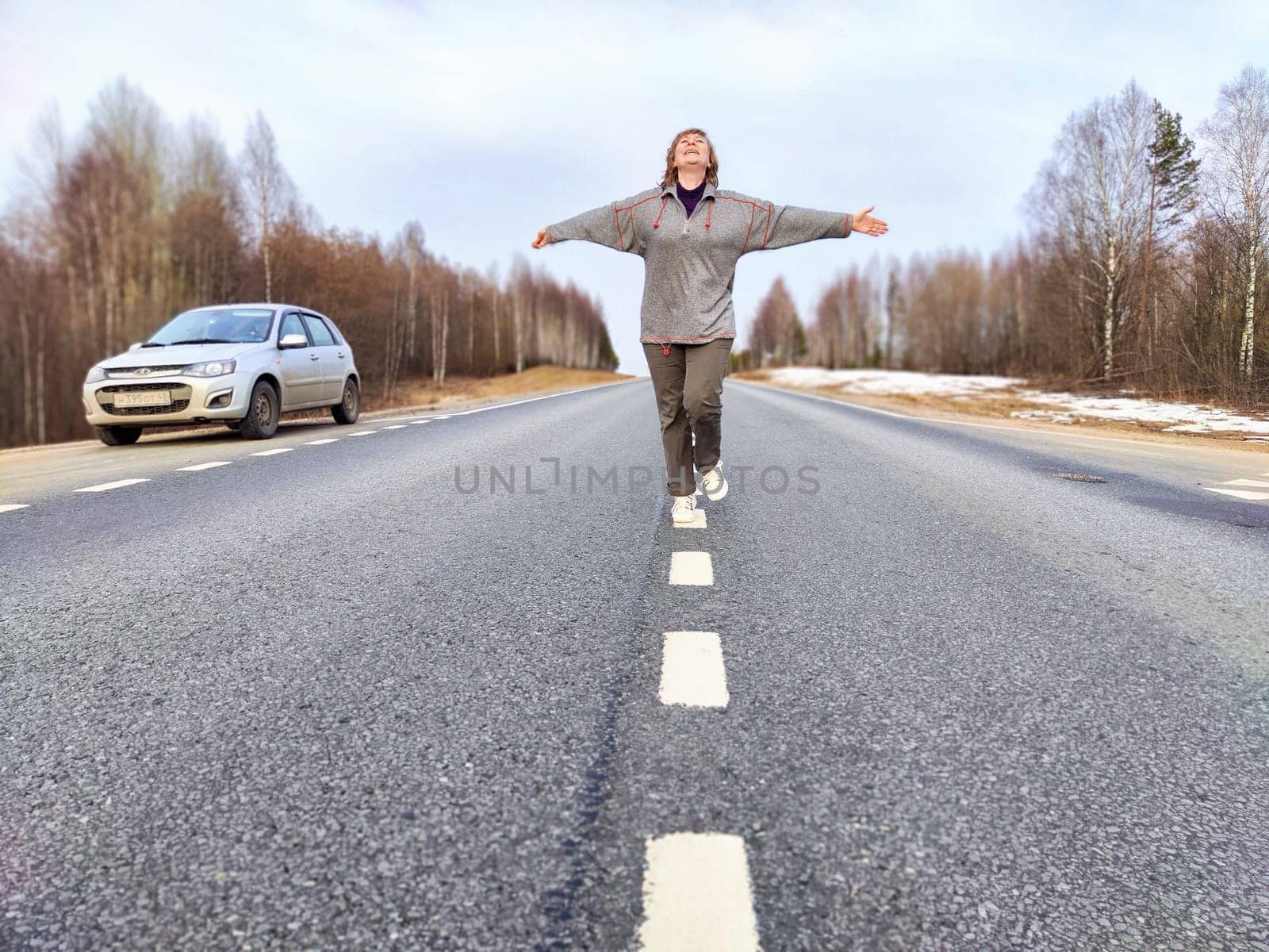 Woman Balancing on Road Marking During Roadside Travel Break. Woman enjoying playful balance walk next to parked car on roadside