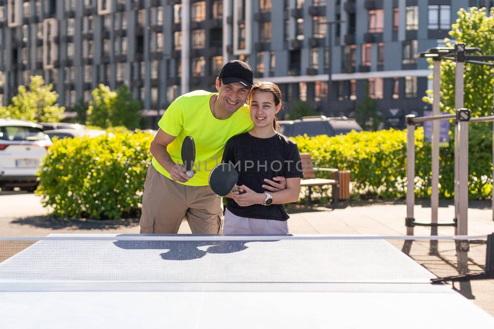 Happy man with his daughter playing ping pong in park. High quality photo