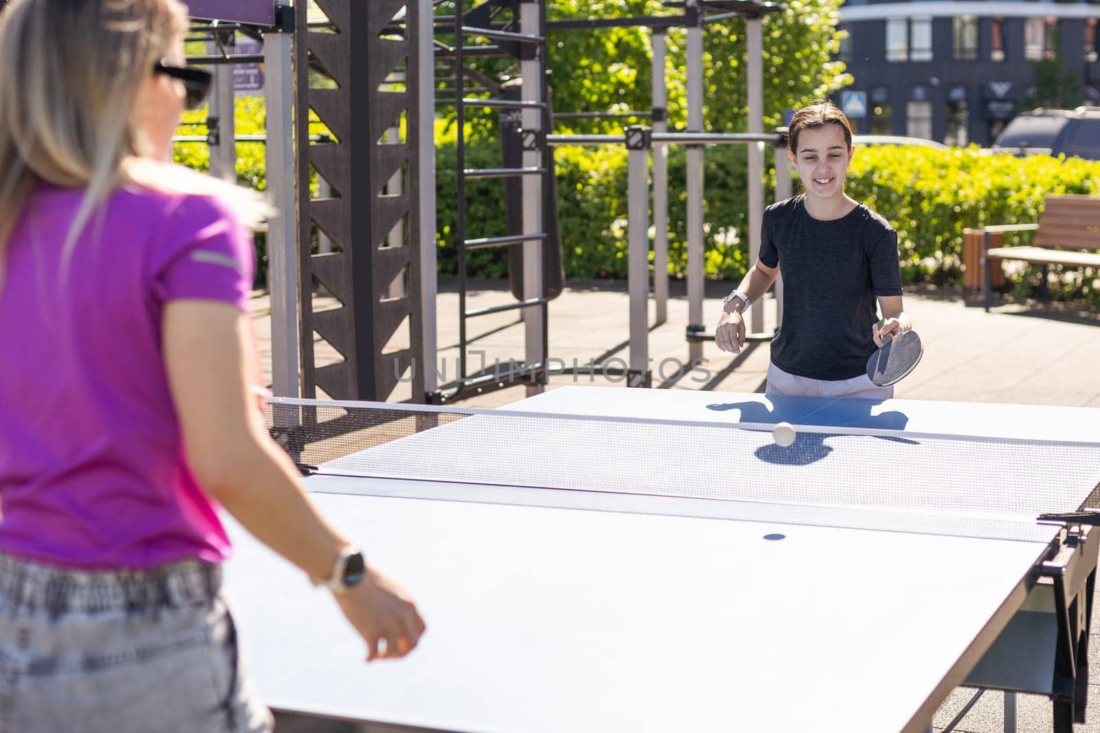 mother and daughter play ping pong in park. High quality photo