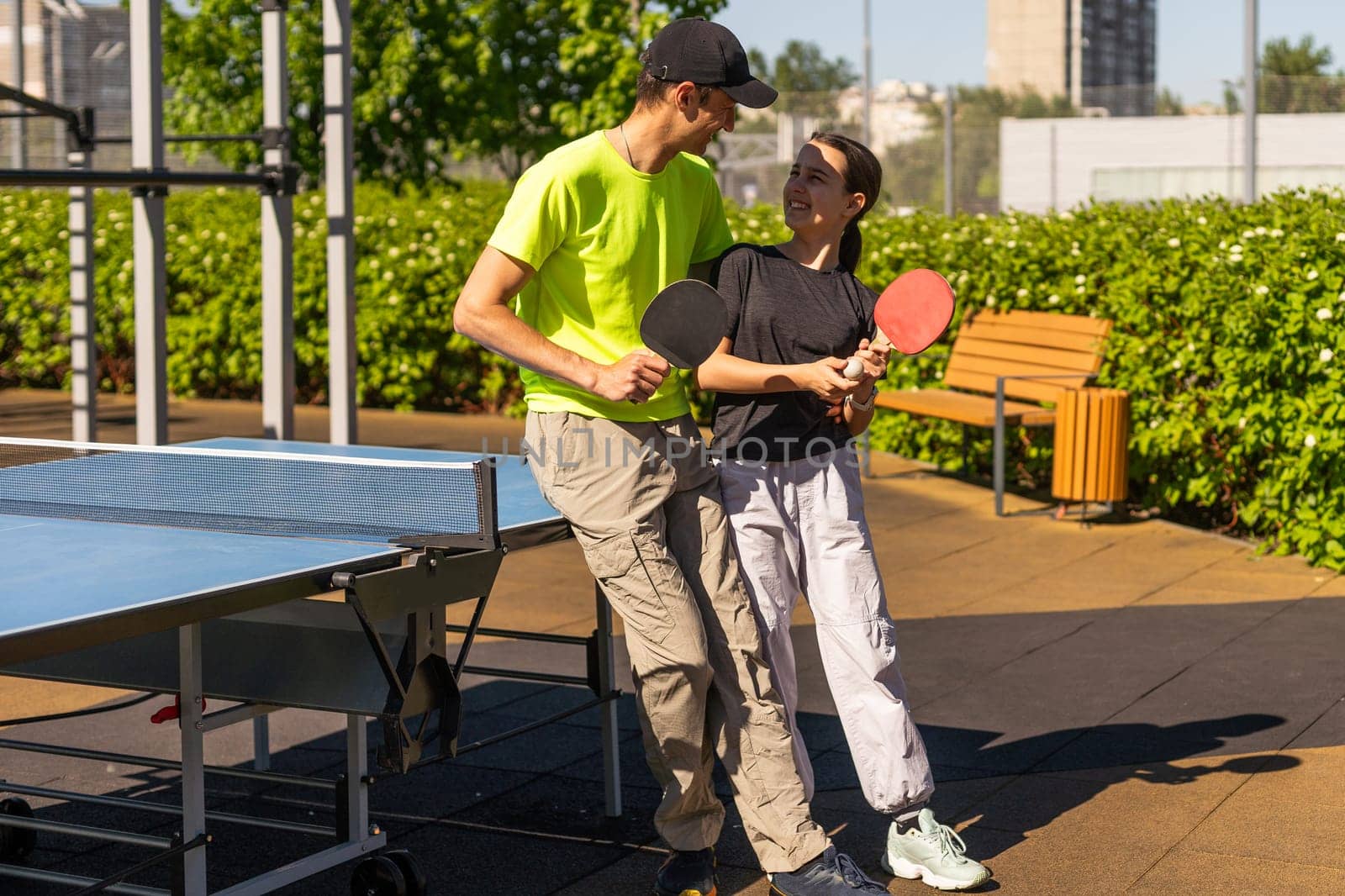 Happy man with his daughter playing ping pong in park. High quality photo