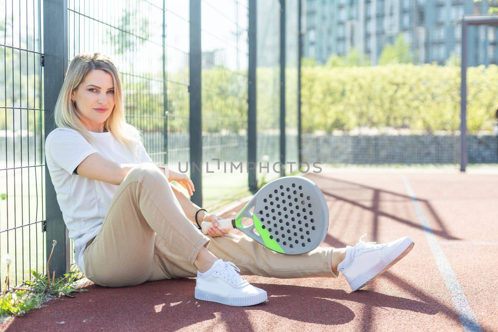 Young sporty woman padel player hitting ball with a racket on a hard court. High quality photo