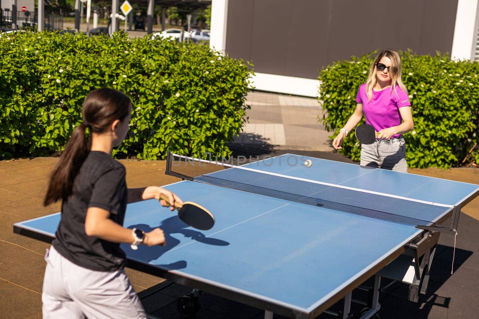 Adult woman instructor teaching girl play table tennis. High quality photo