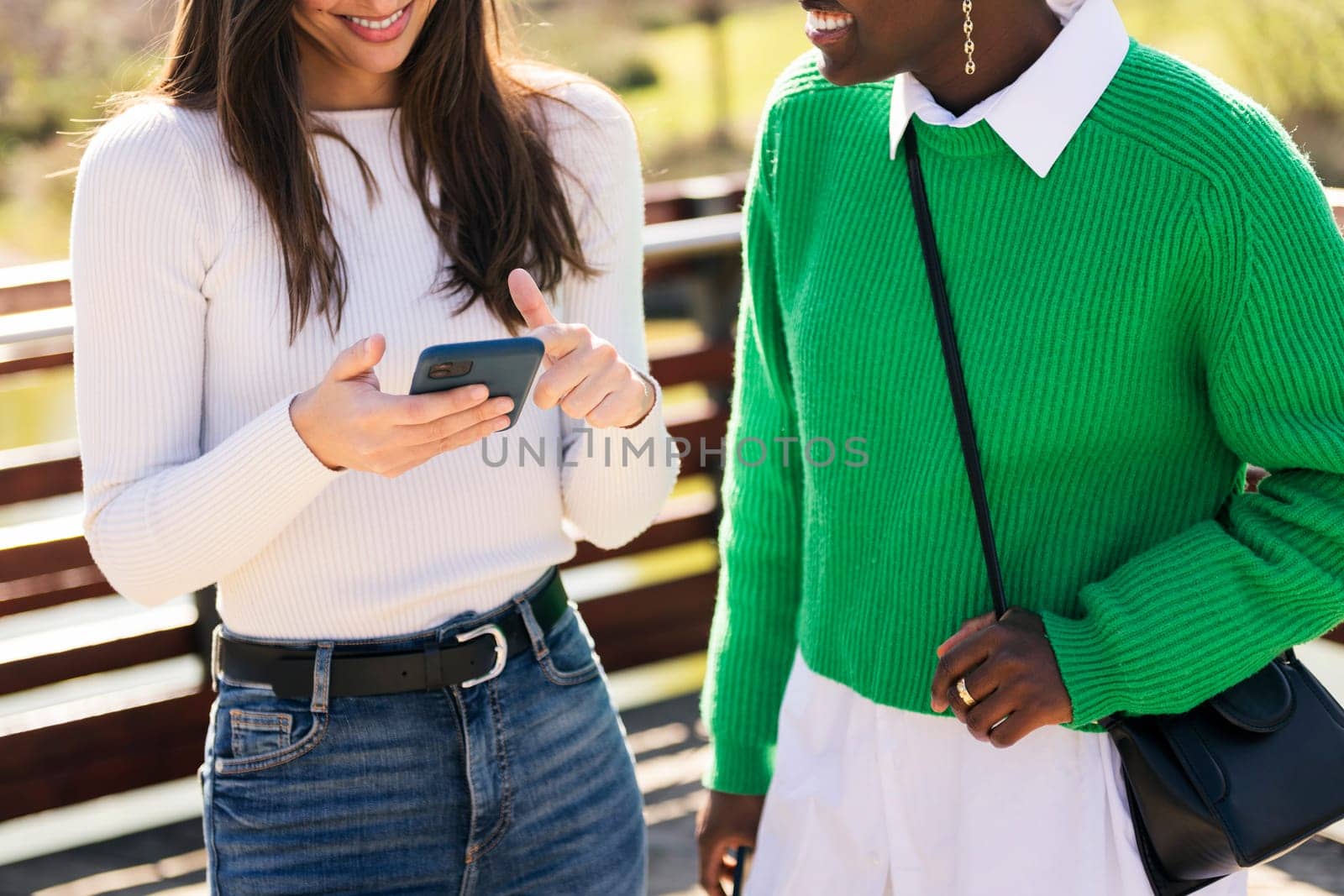 two unrecognizable young women smiling happy using mobile phone, concept of technology of communication and modern lifestyle