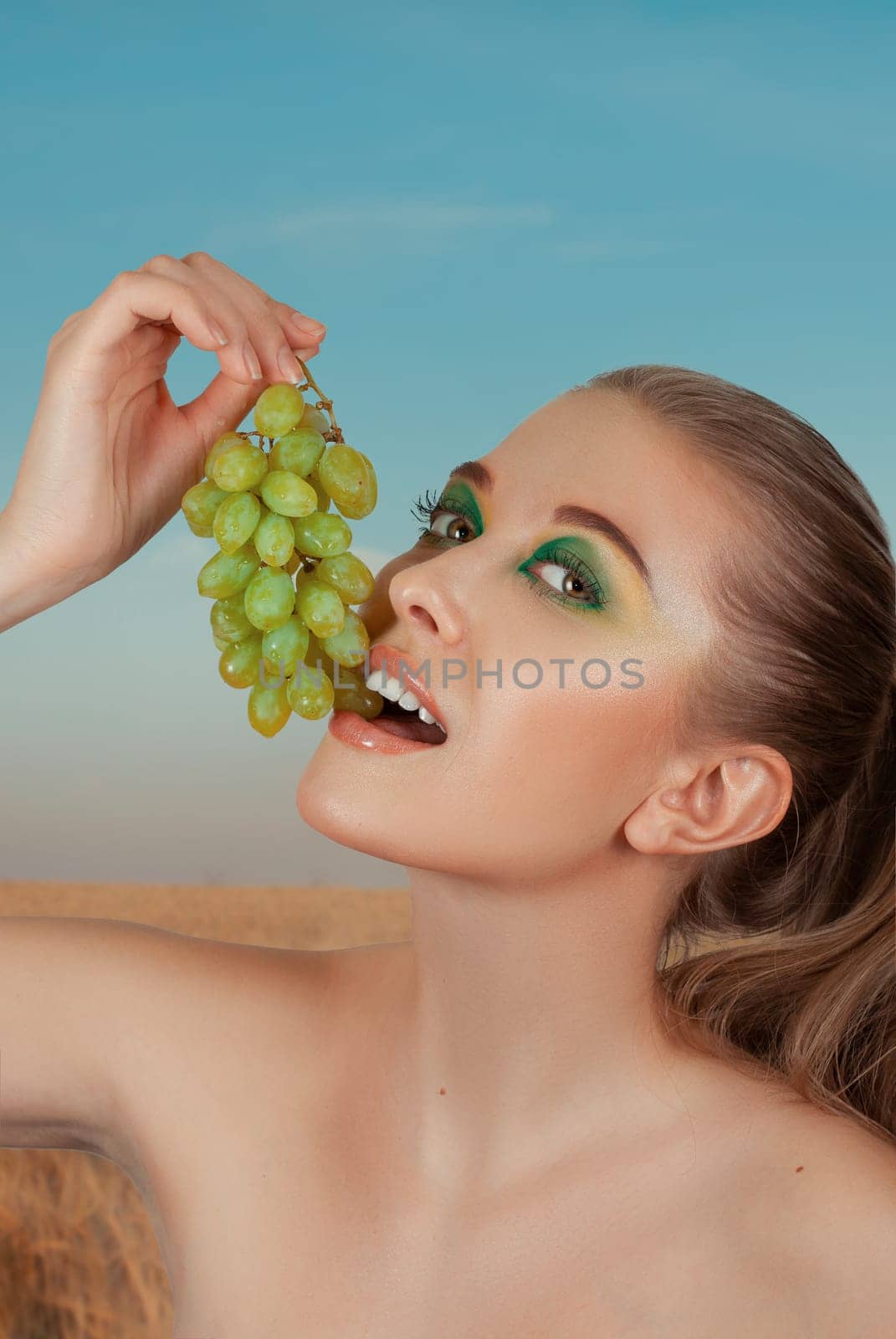 Beautiful young woman with grape bunches on summer green and yellow background