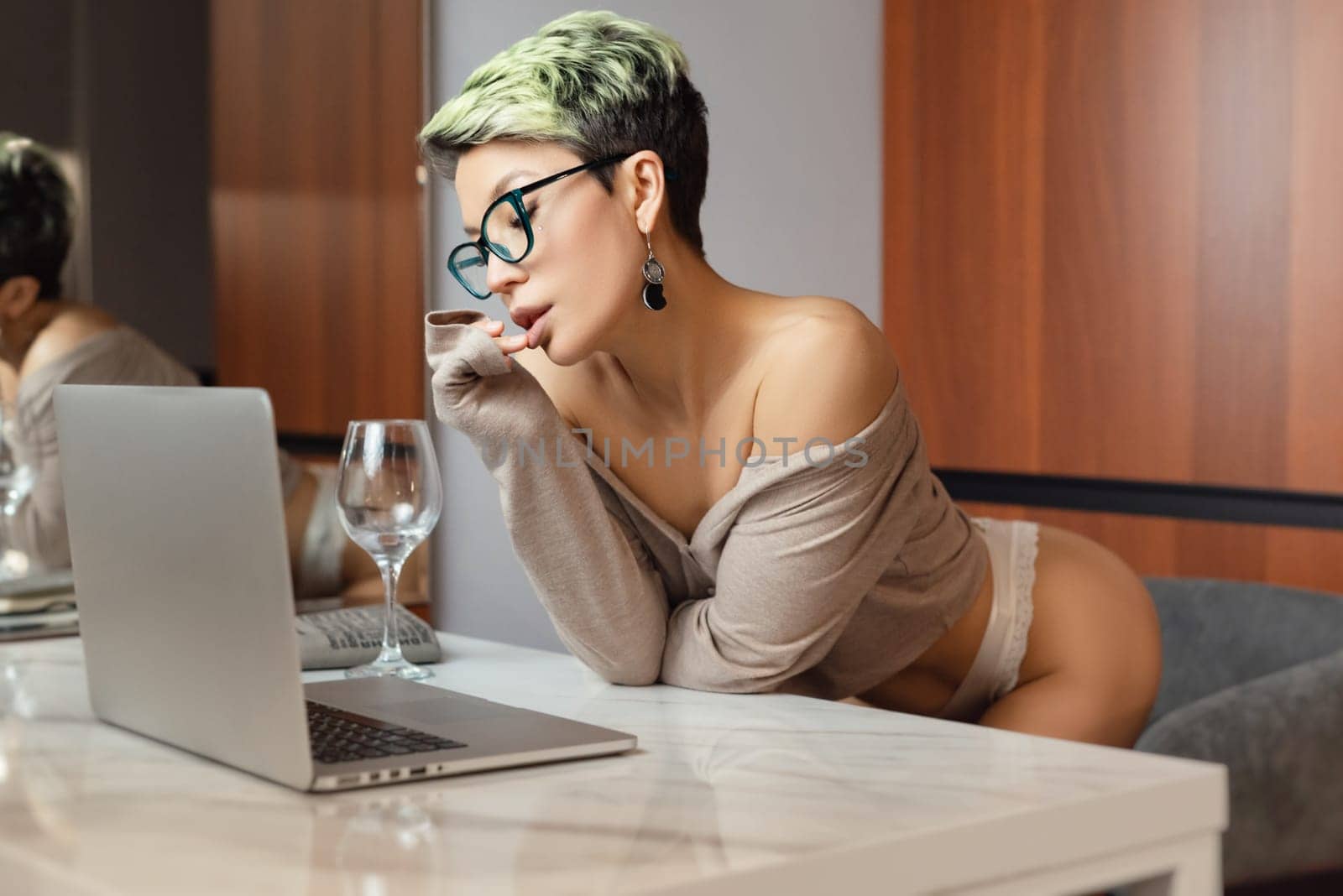 A beautiful girl with short hair in her underwear is sitting sexy in a room at a laptop, working and chatting online by Rotozey