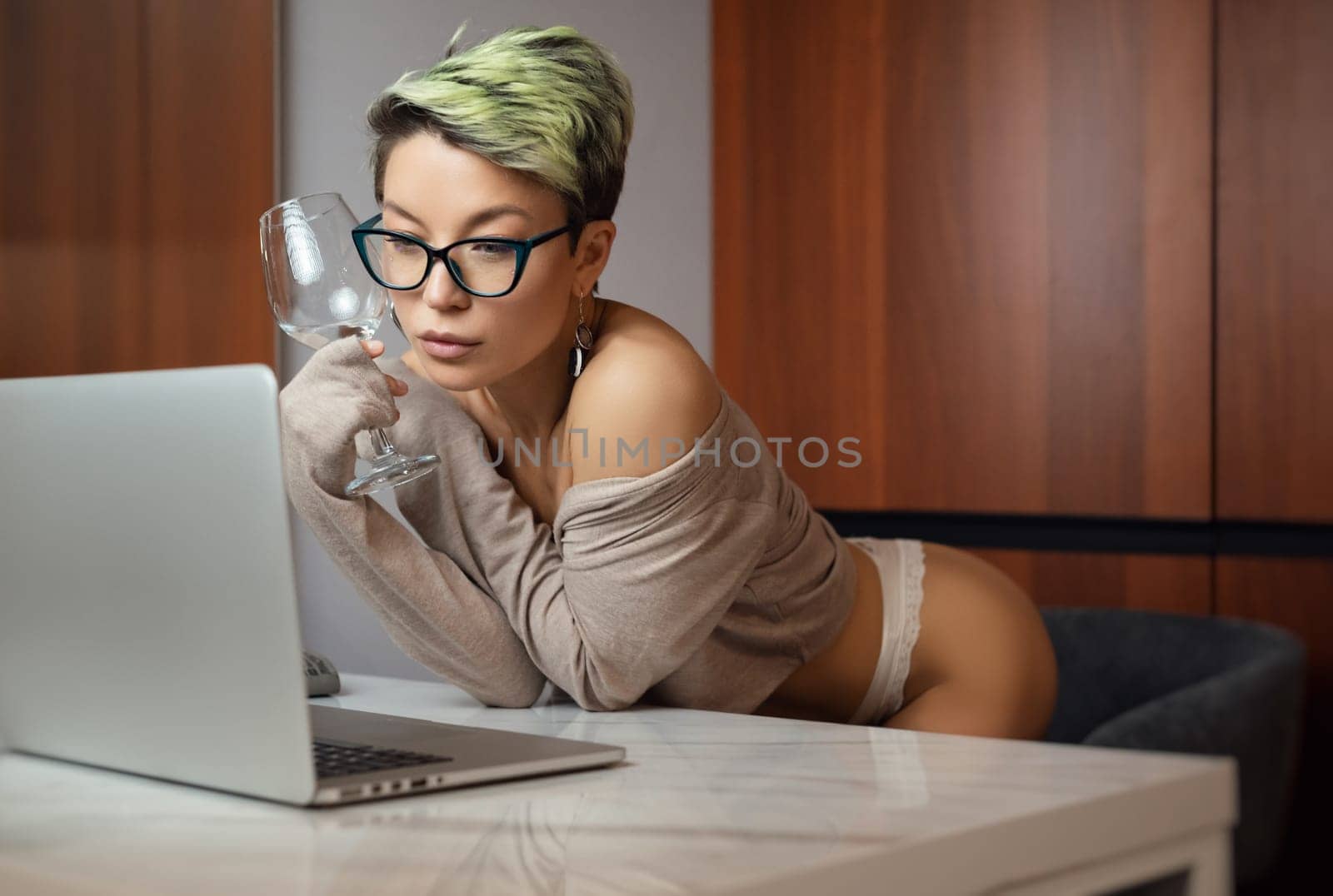 A beautiful girl with short hair in her underwear is sitting sexy in a room at a laptop, working and chatting online by Rotozey