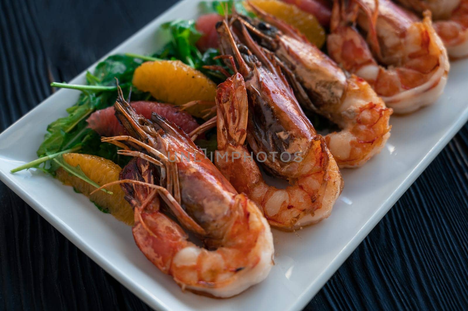 Grilled tiger prawns or shrimps with orange grapefruit and greens on a plate