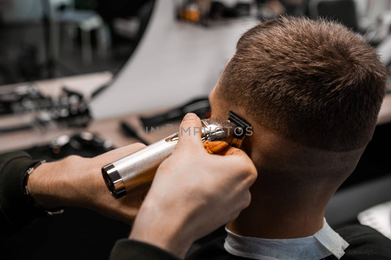 Hairdresser shaves the clients hair on the temple in the stylish barbershop