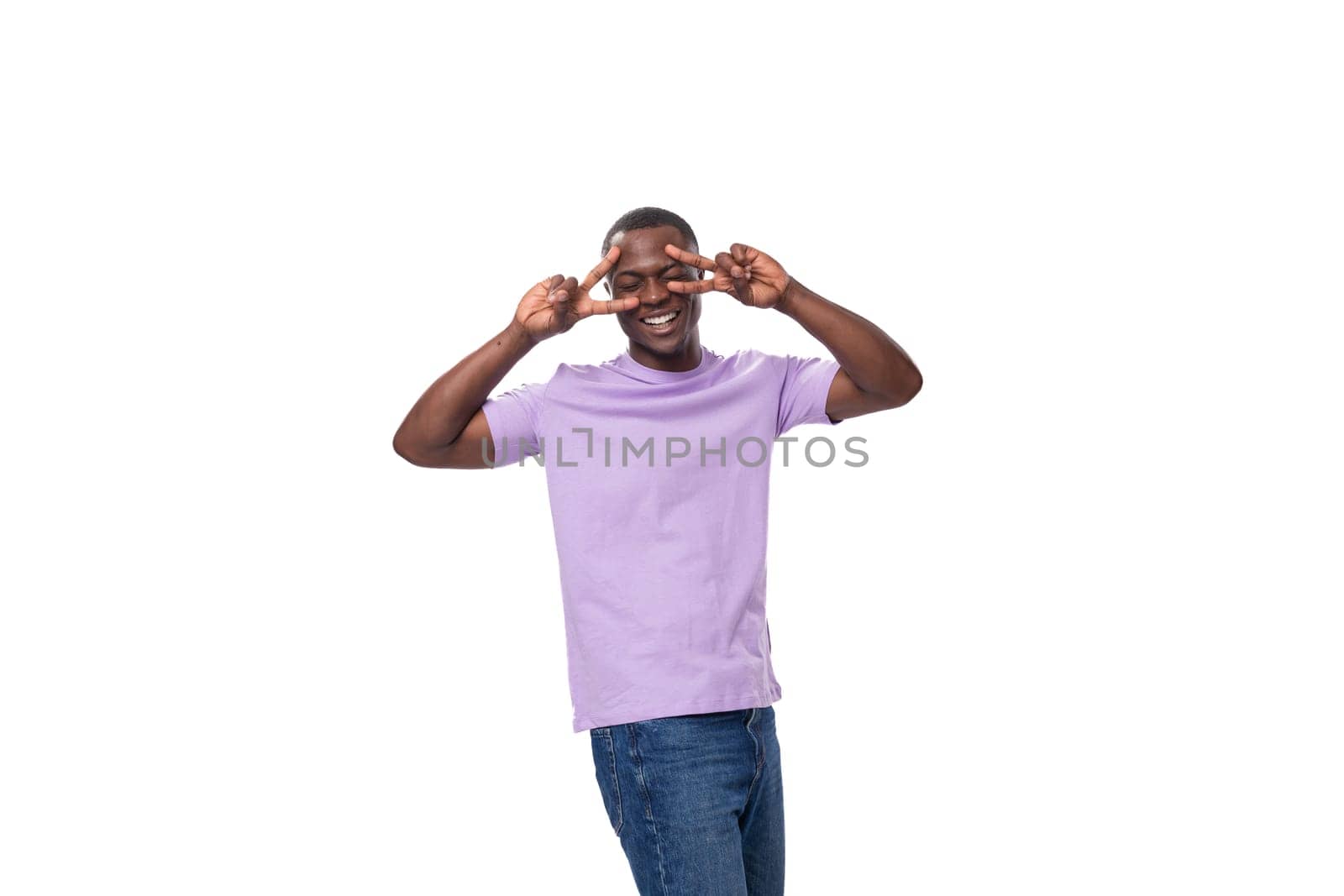 young authentic slender american guy dressed in light lilac t-shirt and jeans.