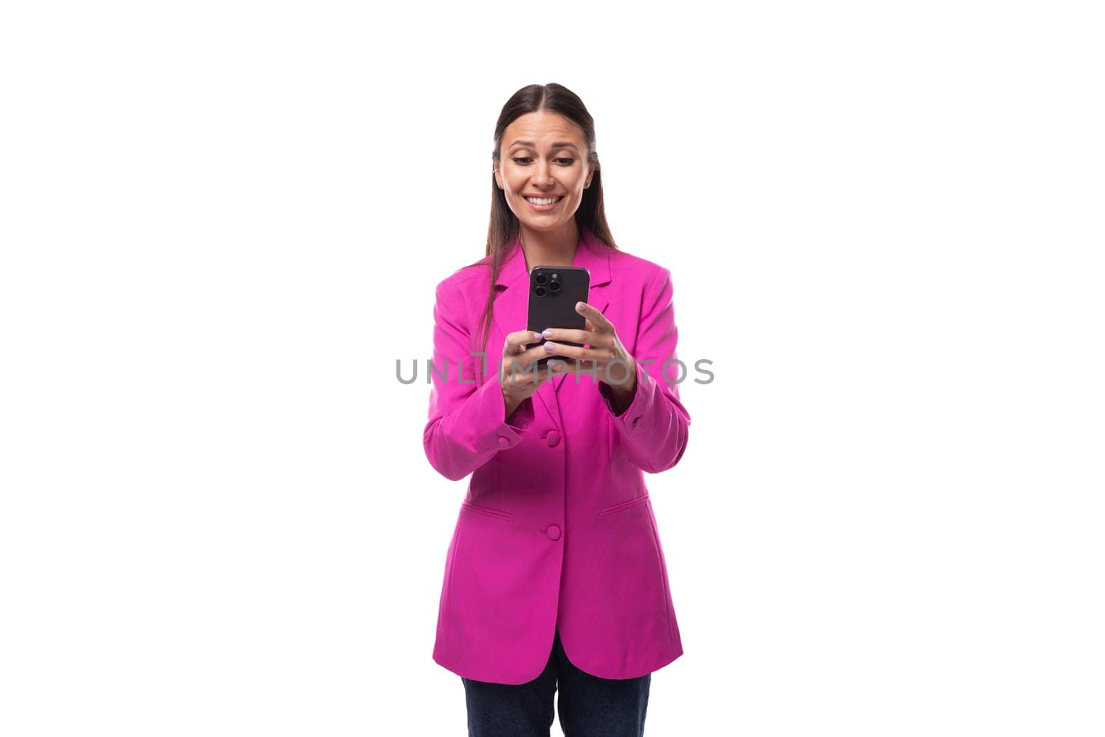 young smart european brunette with black hair dressed in a stylish raspberry jacket is chatting on a smartphone.