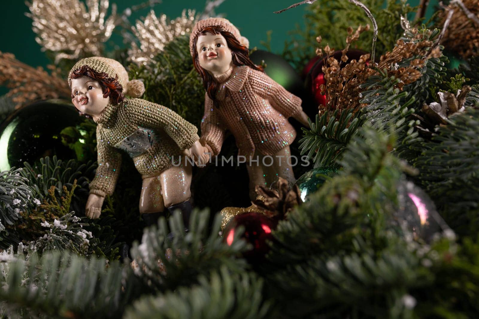 Two small figurines are perched on top of a festive Christmas tree. They are carefully positioned amidst the colorful ornaments and twinkling lights, adding a whimsical touch to the holiday decor.