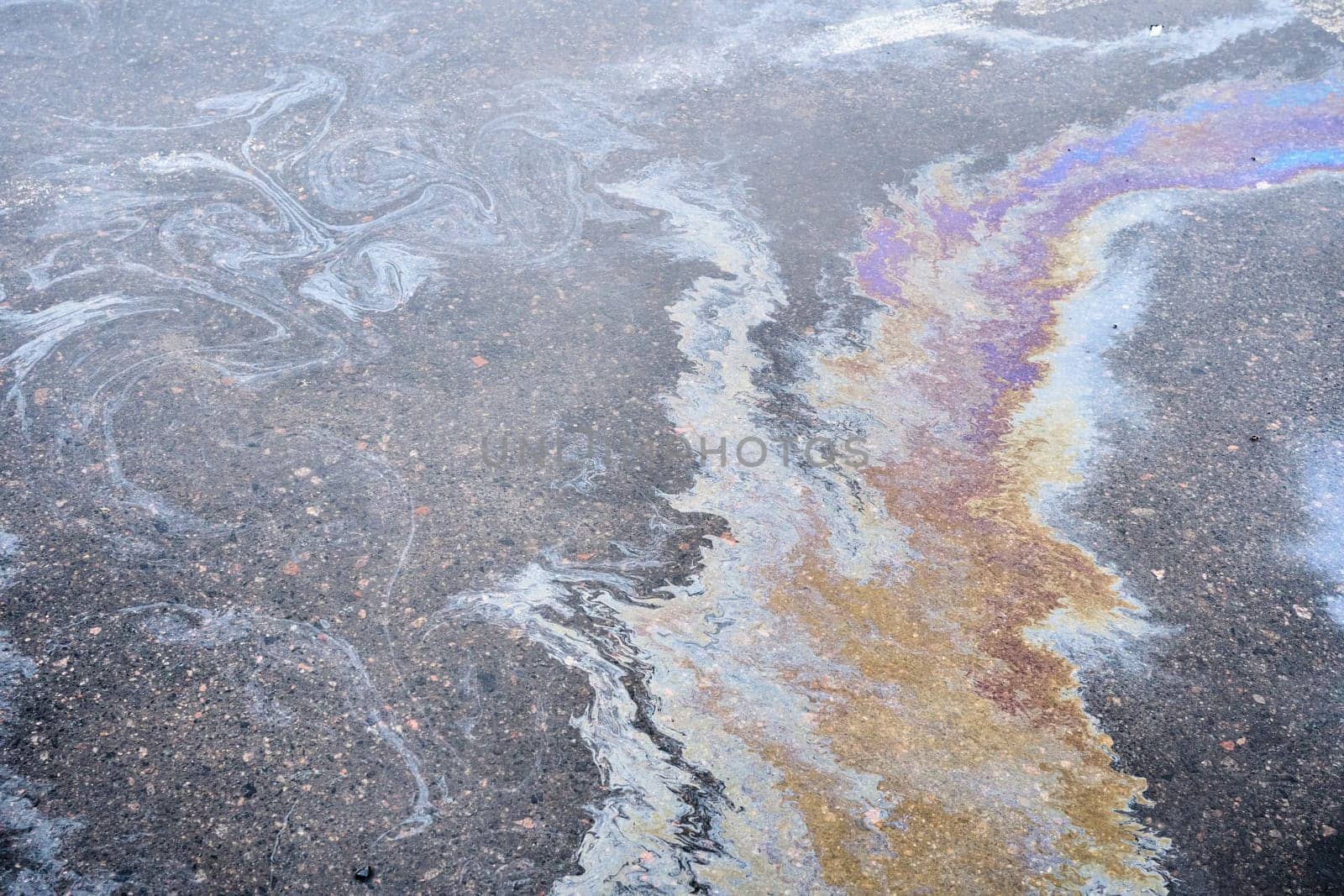 Colored oil stains close-up, color of a gasoline stain on asphalt as a texture or background.