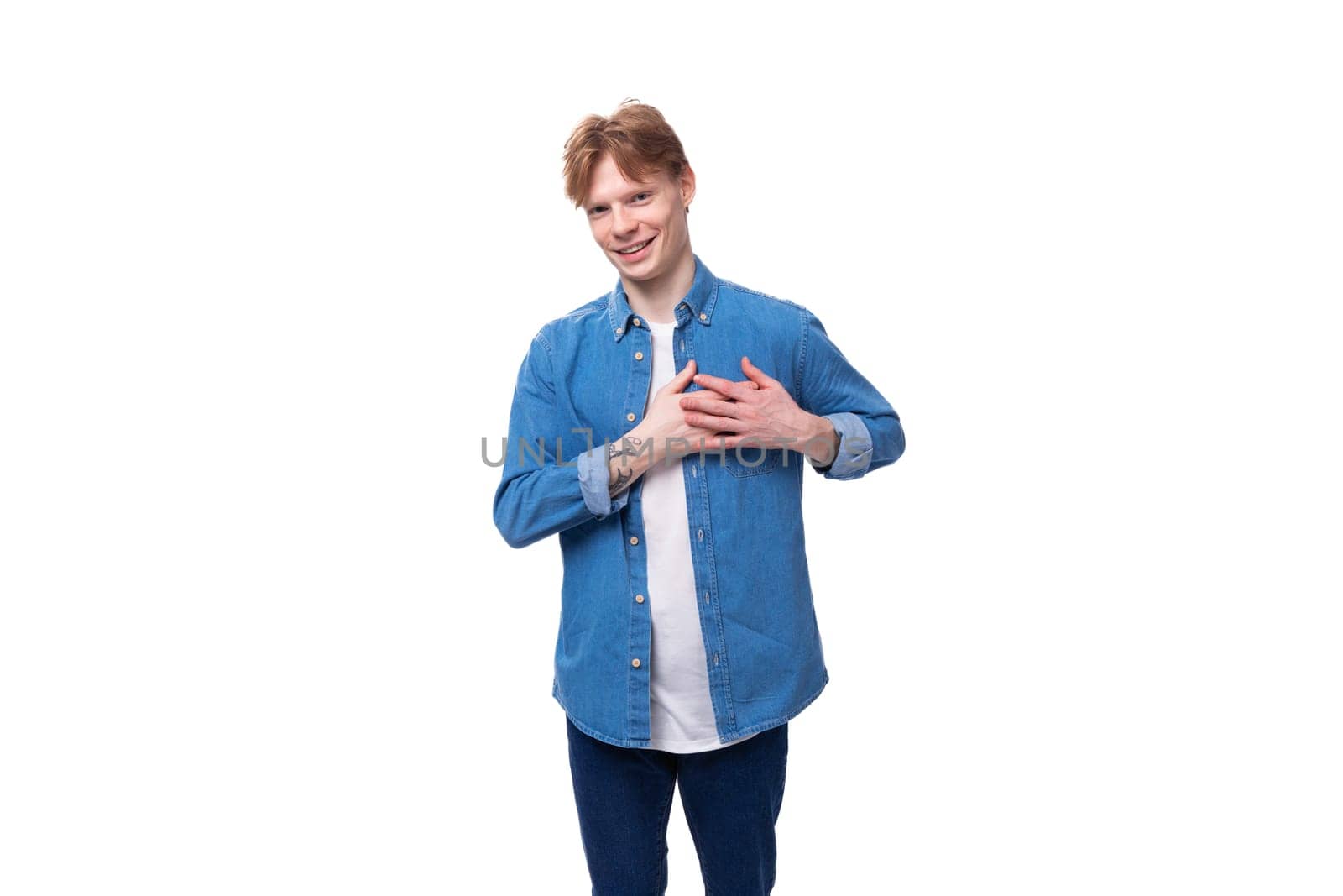 portrait of a european red-haired student guy dressed in a blue denim shirt on a white studio background.