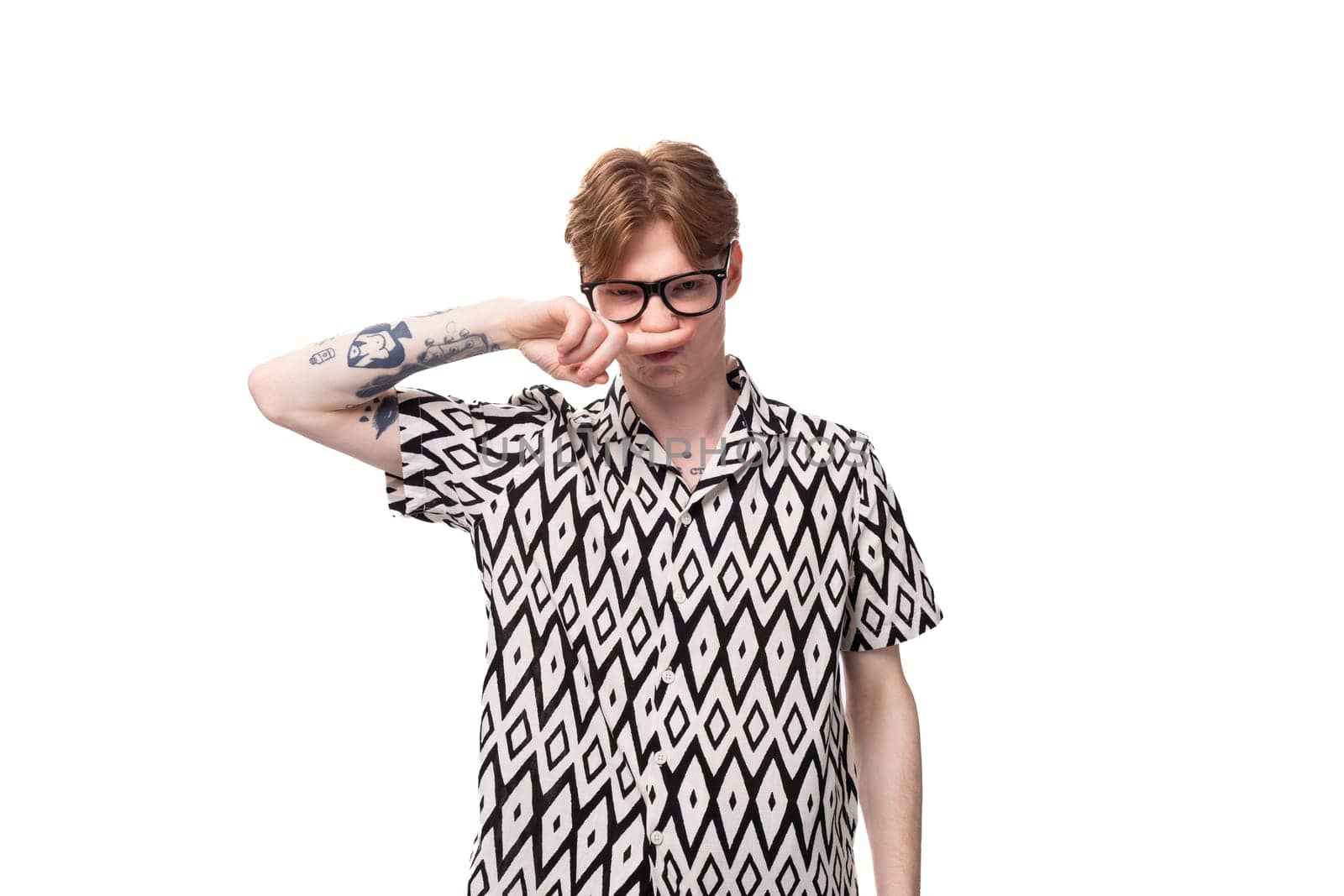 a young european male student with red hair is wearing a shirt with a diamond pattern wears glasses for vision correction.