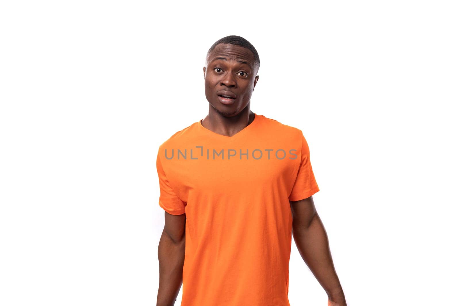 young excited handsome african man dressed in orange t-shirt thinking on studio white background.