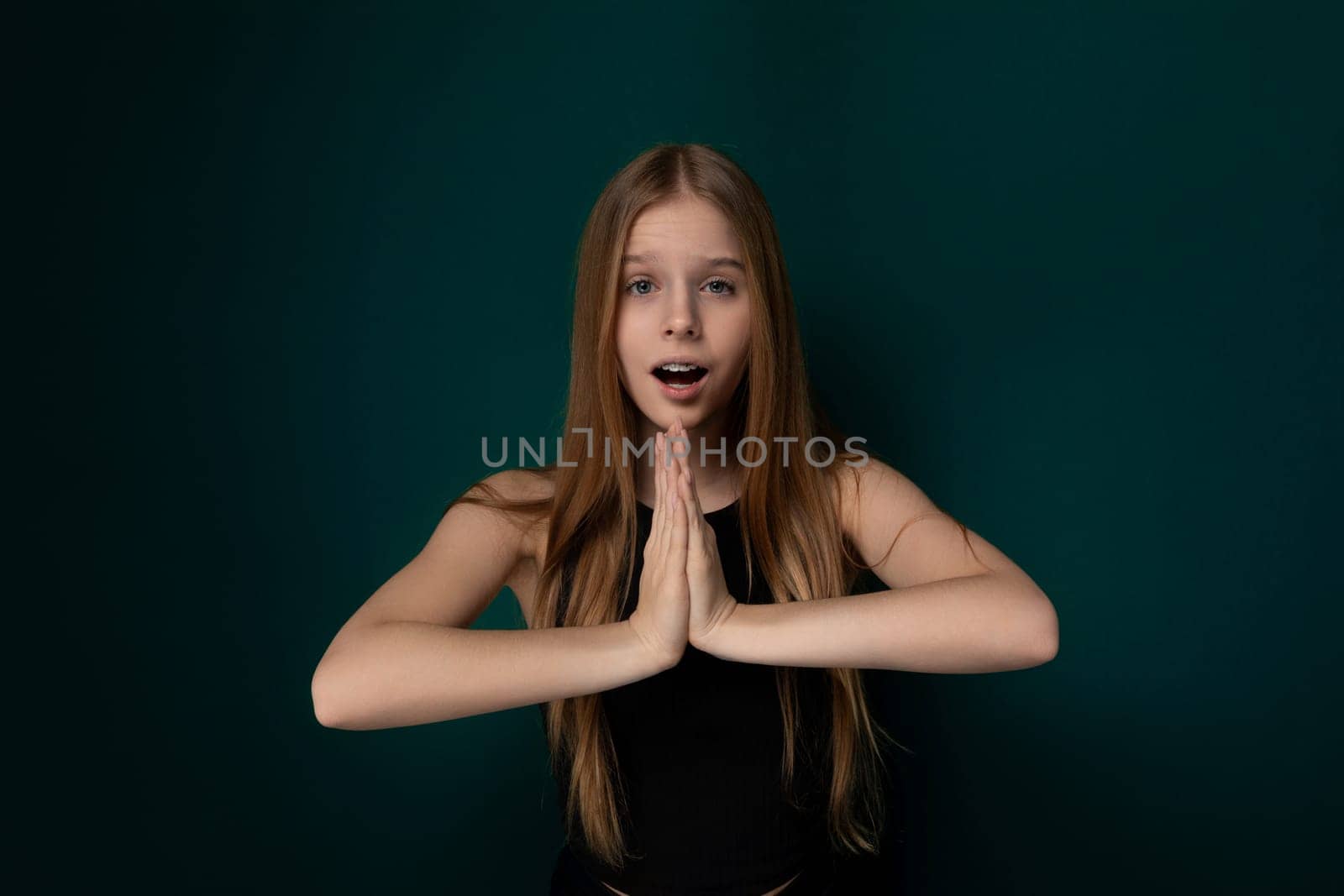 A young girl with a surprised expression on her face, her hands are raised in front of her. She appears startled or shocked by something in her environment. The girls eyes are wide open, and her mouth is slightly agape.