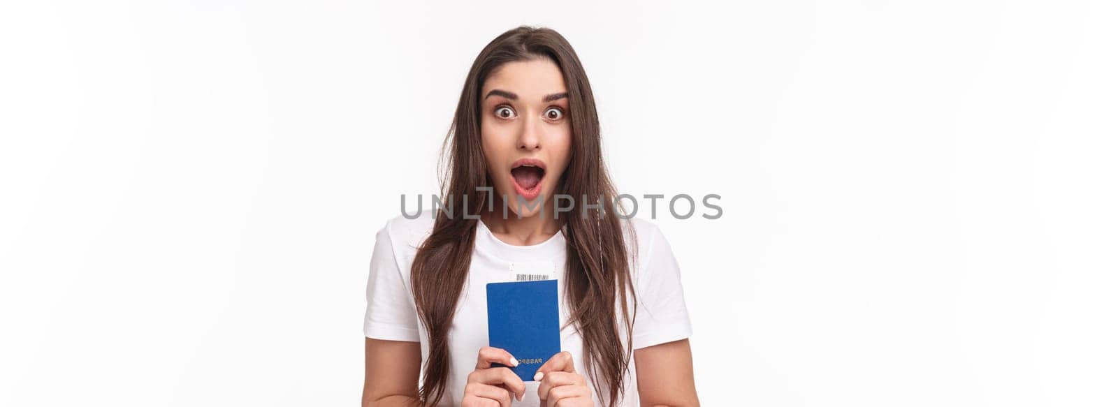Travelling, holidays, summer concept. Close-up portrait of impressed, shocked young woman holding passport, drop jaw and staring astonished at camera, ready to travel, moving abroad.