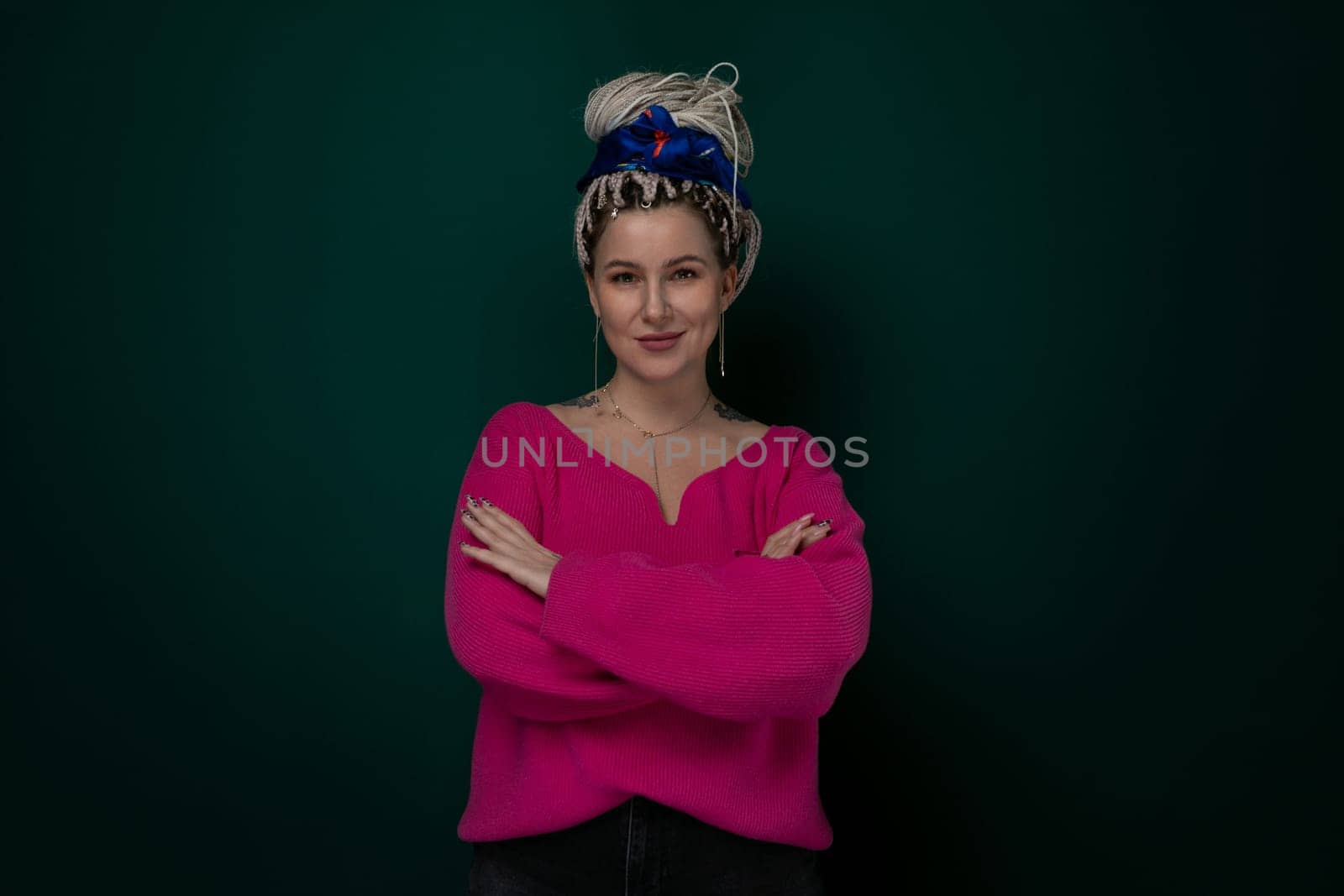 A woman wearing a pink sweater is striking a pose for a picture. She looks directly at the camera with a slight smile. The background is blurred, emphasizing the main subject.