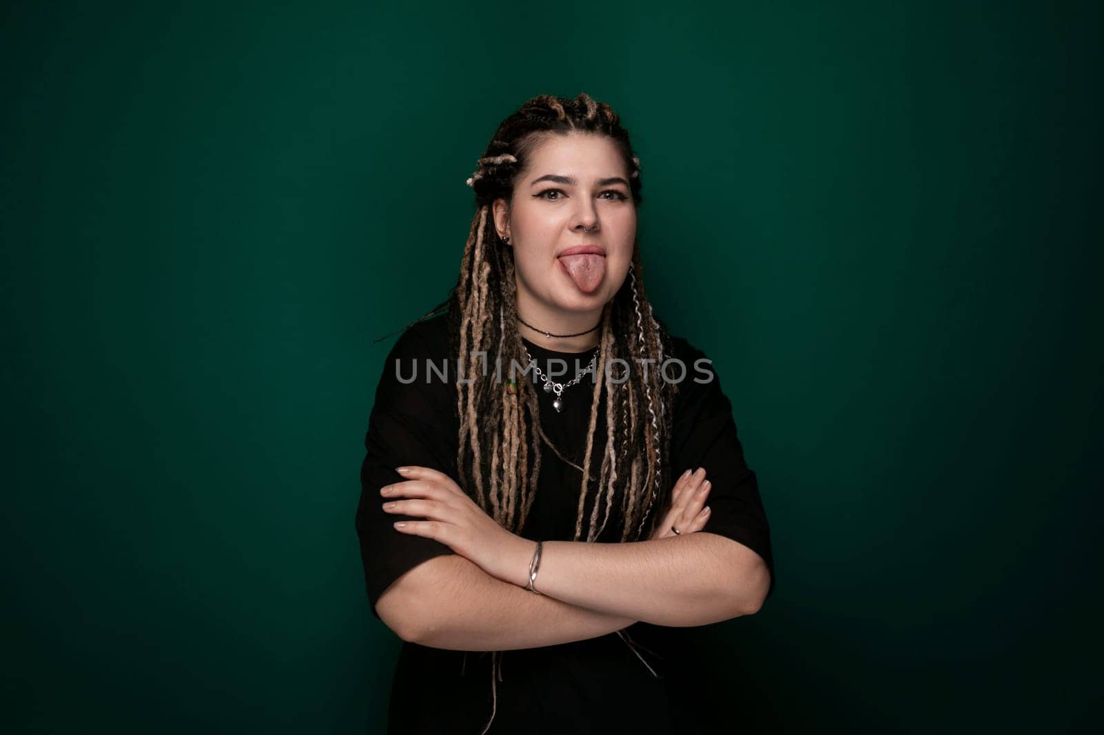 A woman with dreadlocks is contorting her face into a humorous expression, showcasing a lighthearted moment of joy and playfulness.