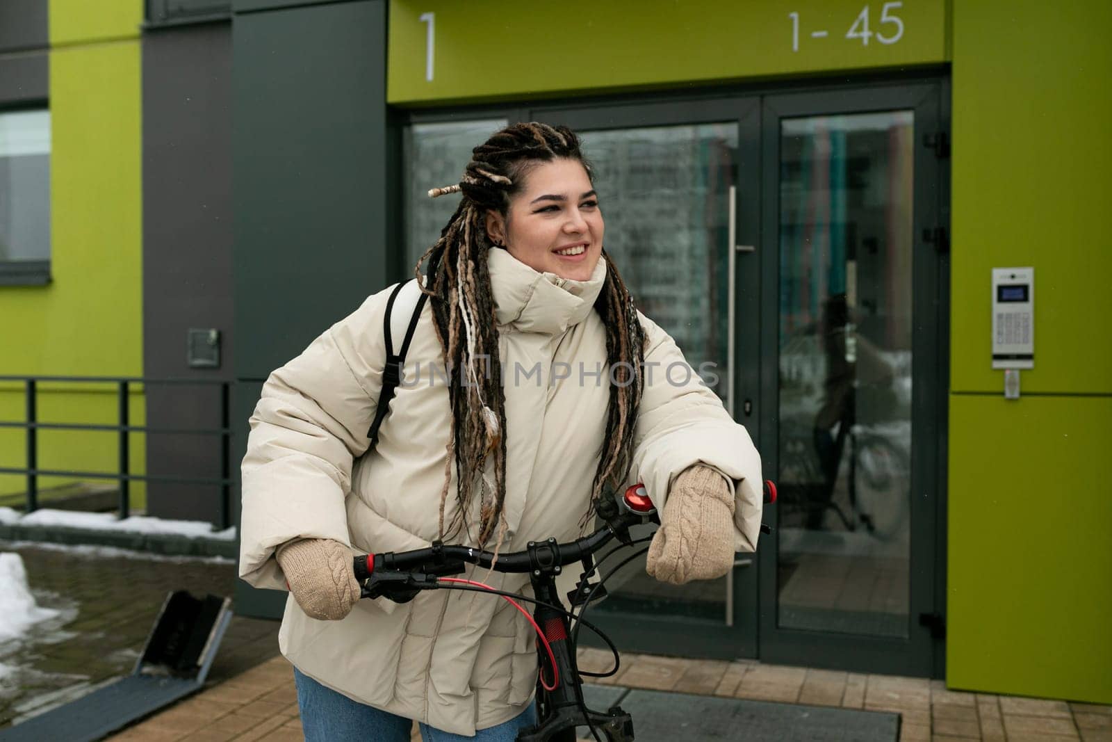 A woman with dreadlocks is energetically riding a bike down a city street. She is dressed casually and confidently navigates through traffic with ease.