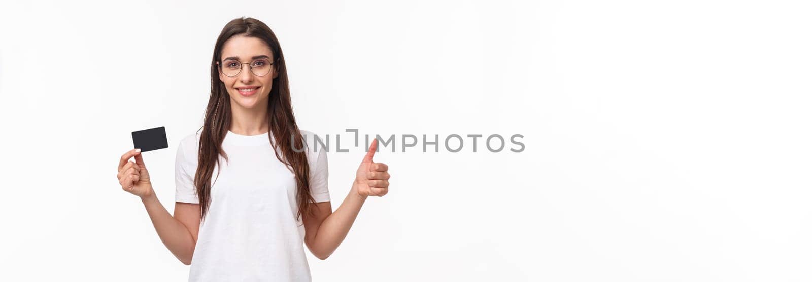 Portrait of confident and happy, smiling young woman in t-shirt, glasses, show thumbs-up and nod in approval, recommend bank, show credit card, buying online with non-cash payment.