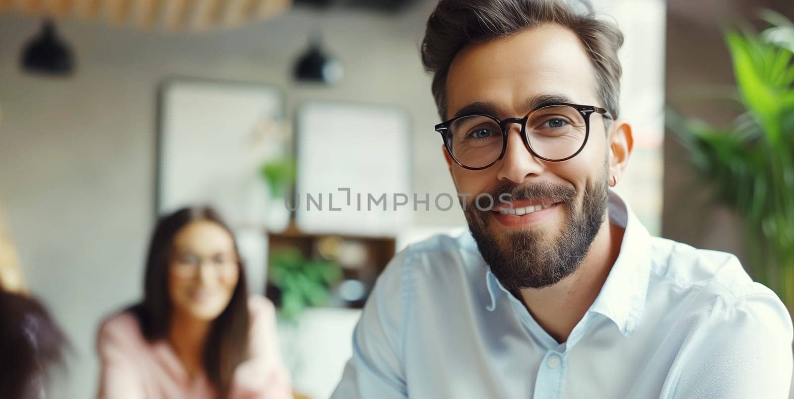 Portrait of happy smiling modern business man in glasses in office sitting at desk and working at the laptop