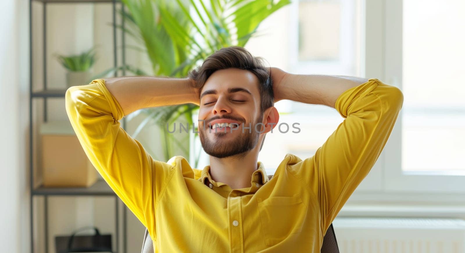 Happy relaxed young man enjoying sitting at desk during working at the laptop at home with green plants, female freelancer or student