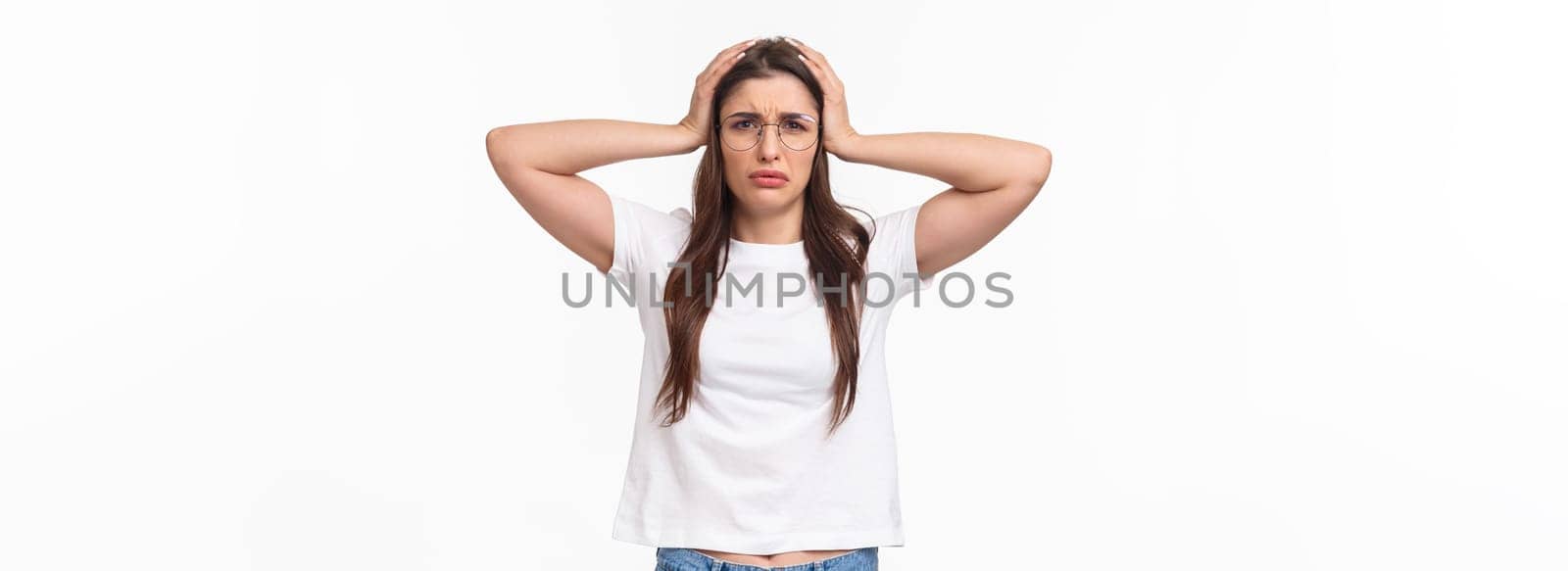 Waist-up portrait of troubled female student have big problem, grab head frowning and grimacing facing complex situation, dont know what do, standing desperate and embarrassed.