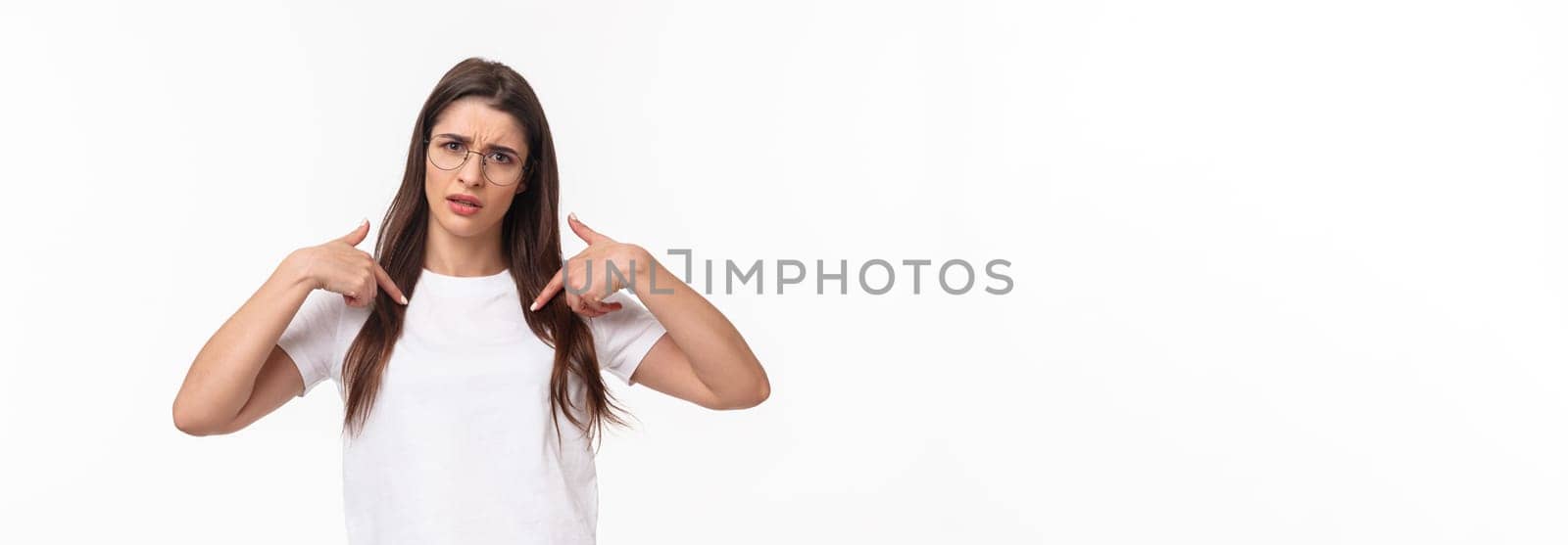 Waist-up portrait of insulted, shocked and offended young frustrated woman pointing at herself, grimace puzzled and confused, cant understand why she was picked or accused.