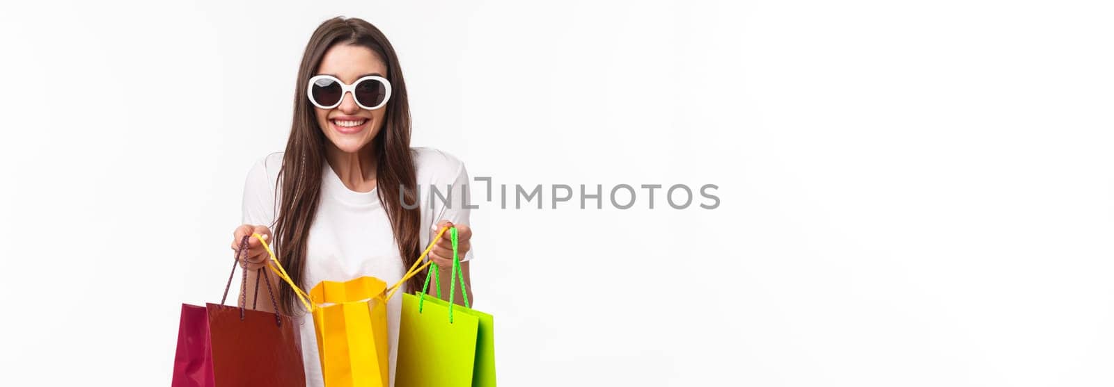 Shopping, leisure and lifestyle concept. Portrait of excited happy young girl likes shop, attend favorite mall, got lots of new clothes, bragging it, open up bag to show friend, smiling enthusiastic.