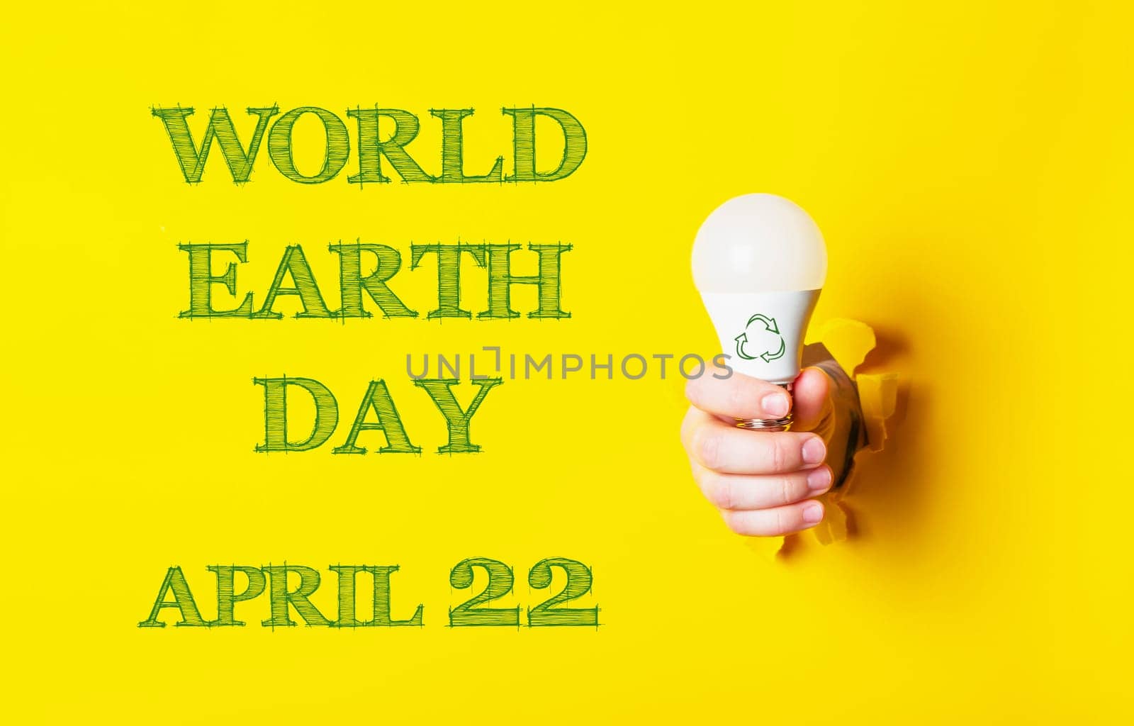 A person holding a light bulb with the words World Earth Day on the background. The image is yellow and green