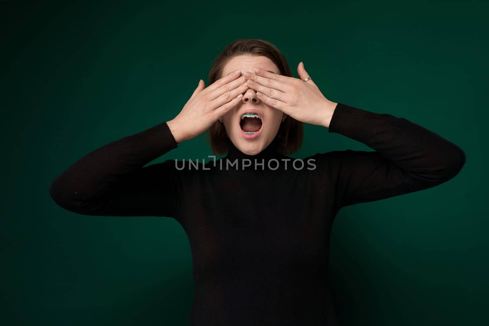 A woman is shown with her hands covering her eyes. She appears to be shielding her eyes from something unseen, possibly using the gesture to convey feelings of distress, fear, or uncertainty.