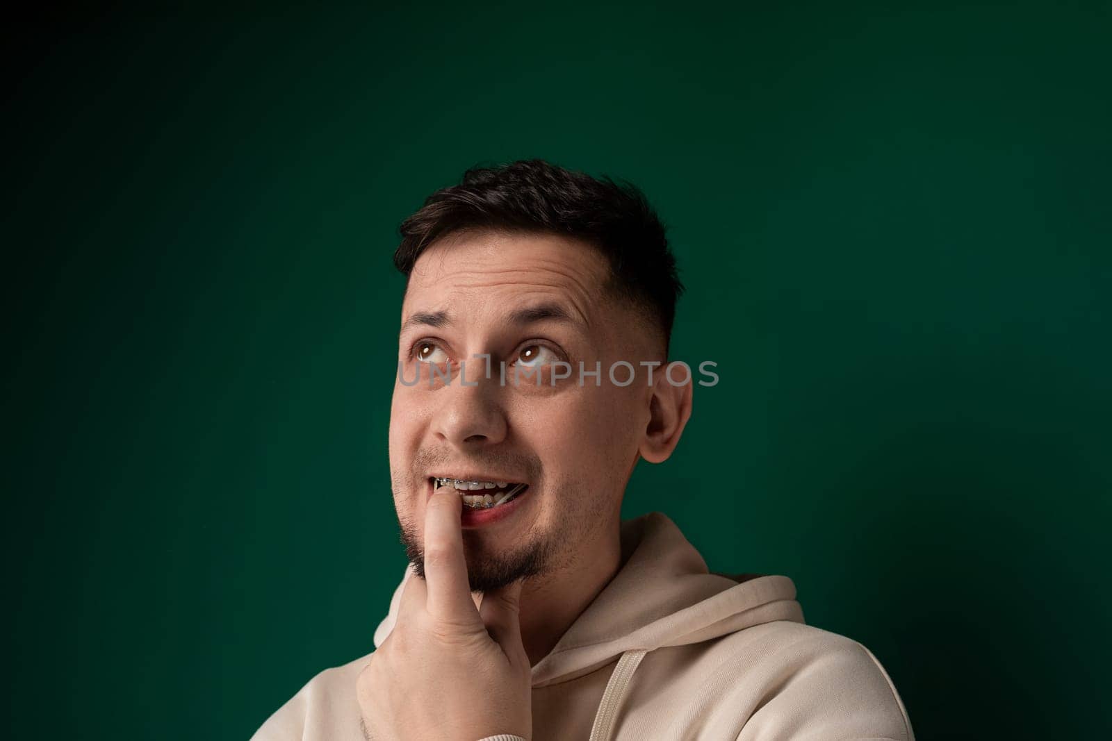 A man contorts his face comically as he uses his finger to manipulate his features, creating a humorous expression.