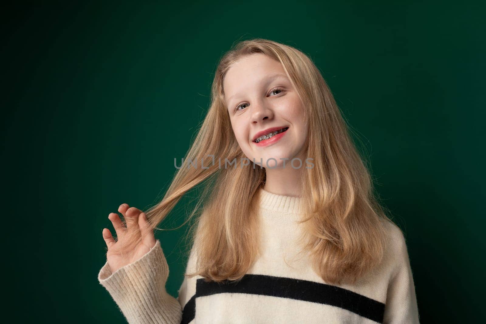 A young girl with long blonde hair is smiling in this portrait. Her bright smile lights up her face as she looks directly at the camera, radiating happiness.