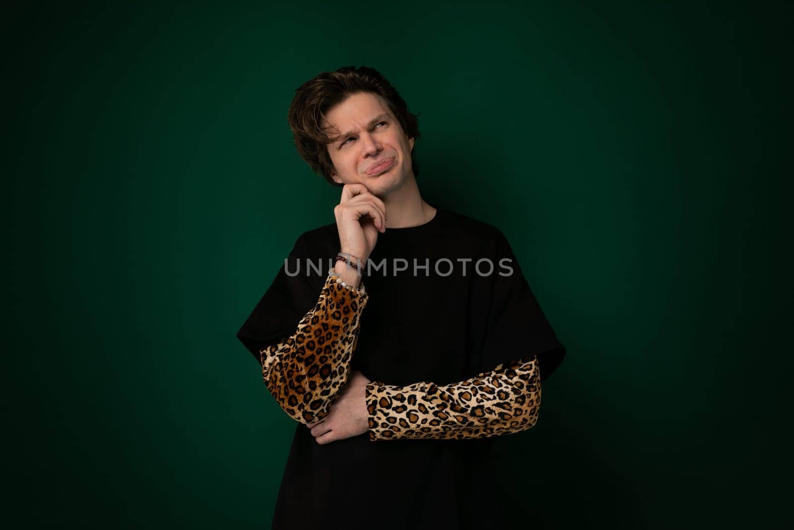 A woman striking a pose in front of a vibrant green background. She is elegantly positioned, showcasing confidence and style.