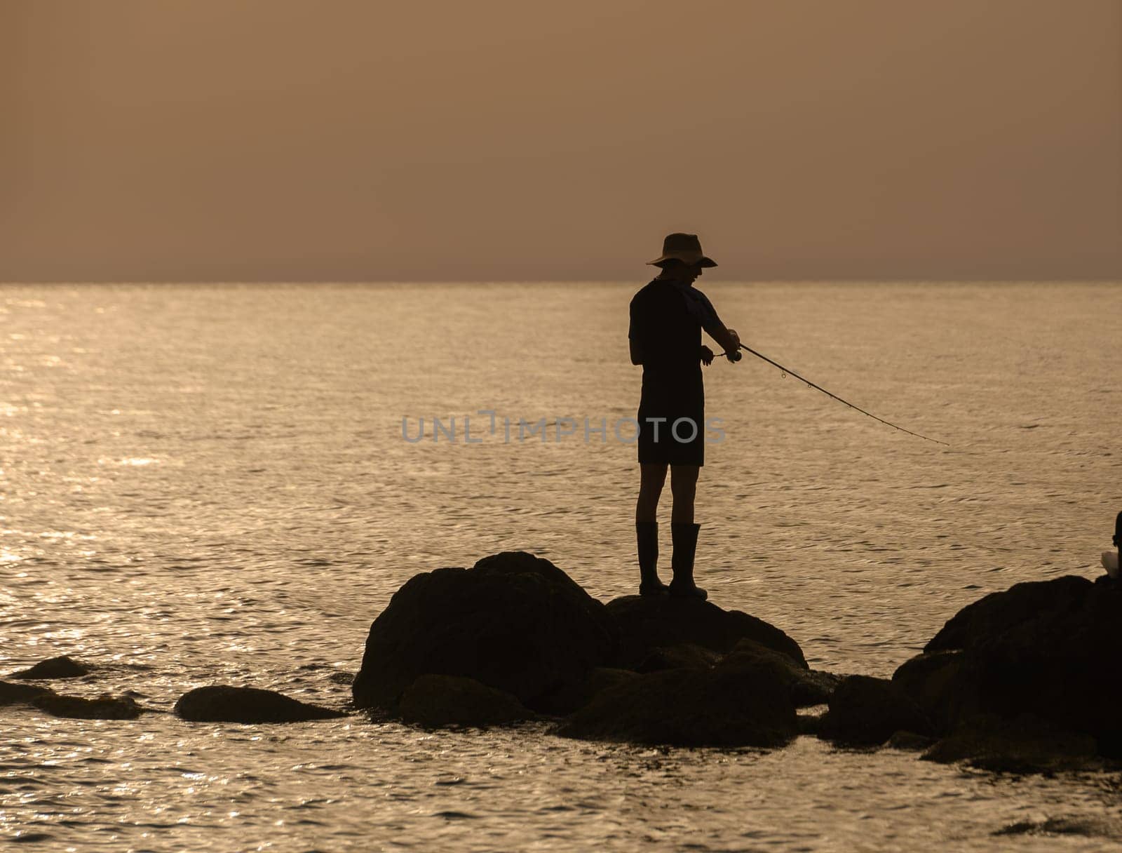 Gazeveren Cyprus -05.18.2024 fisherman catches fish on the rocks on the seashore by Mixa74