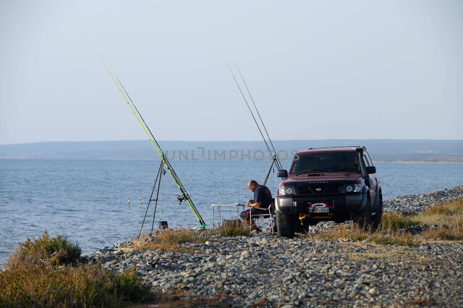 Gazeveren Cyprus -05.18.2024 fisherman catches fish on the seashore by Mixa74